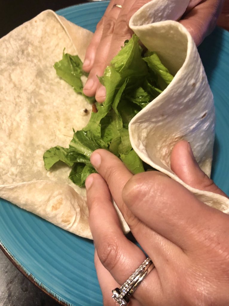 folding the chicken Caesar wrap on a light blue plate