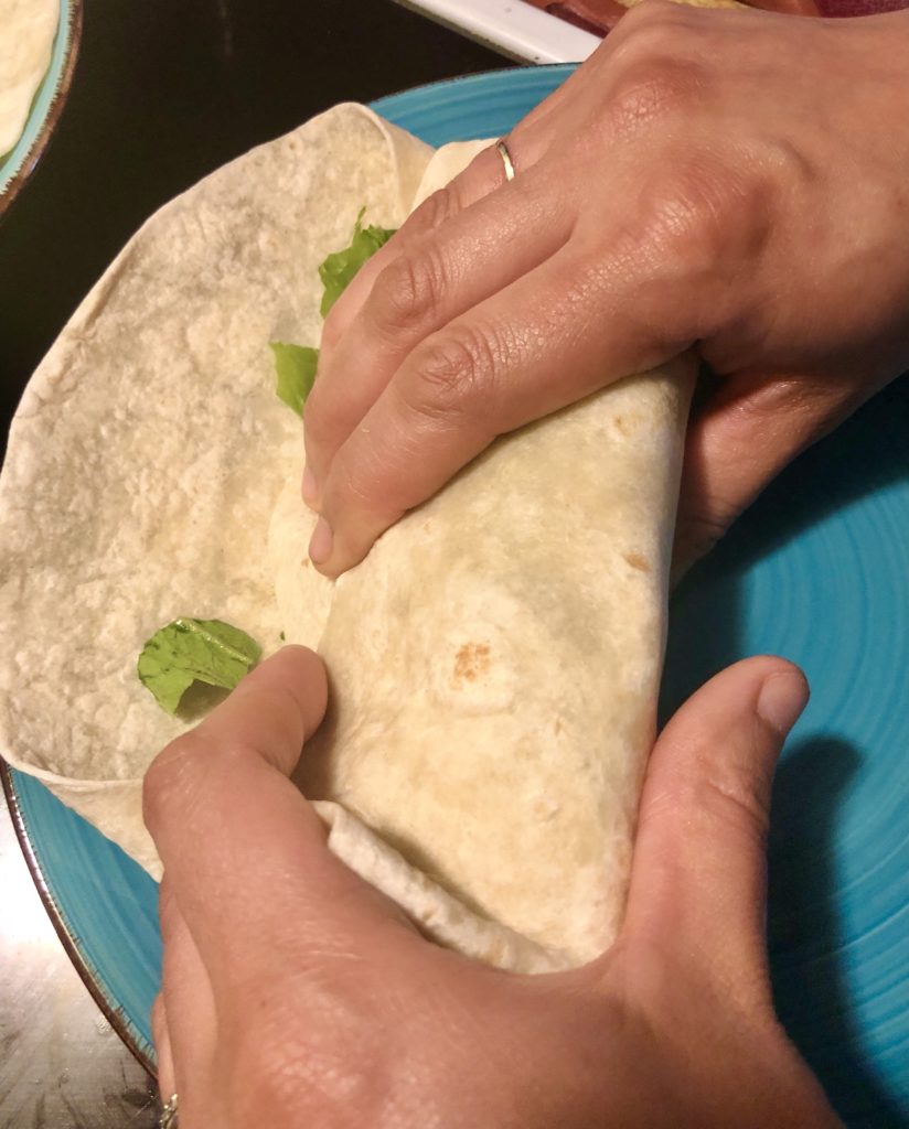 rolling chicken Caesar wrap on blue plate