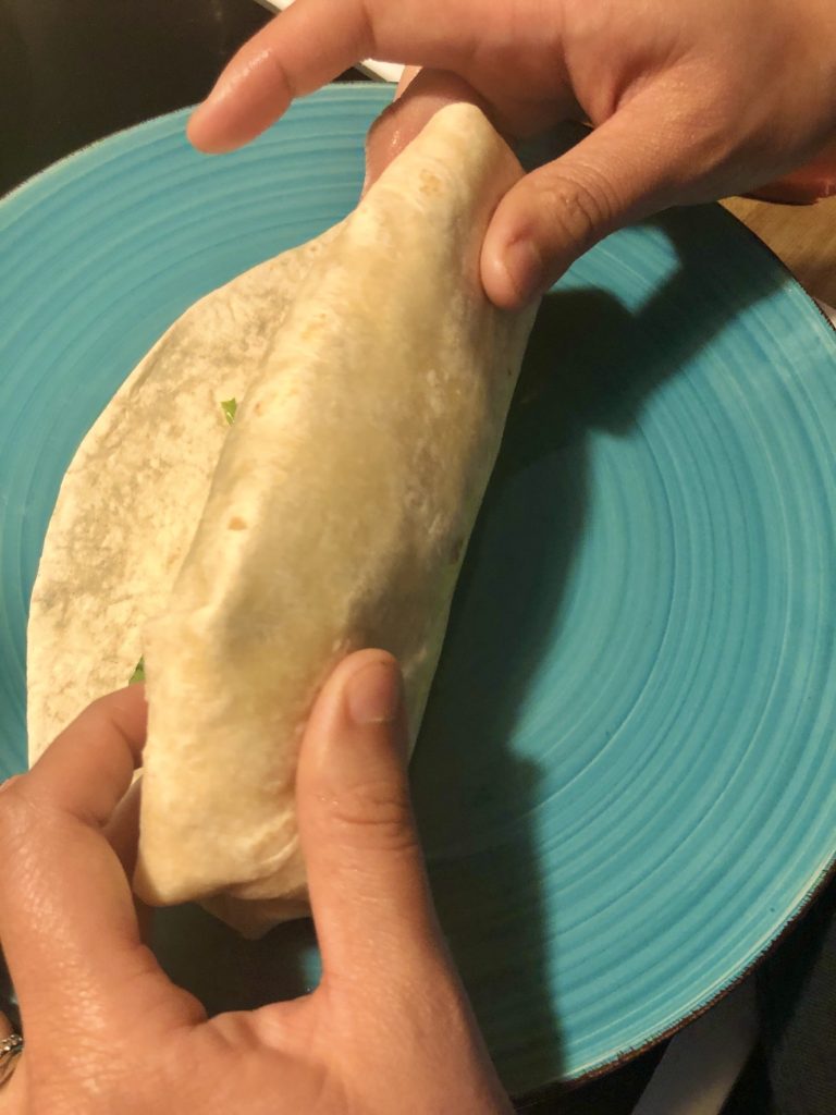 wrapping chicken Caesar wrap on blue plate