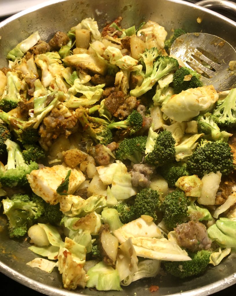 Stirring Thai yellow curry in large silver frying pan