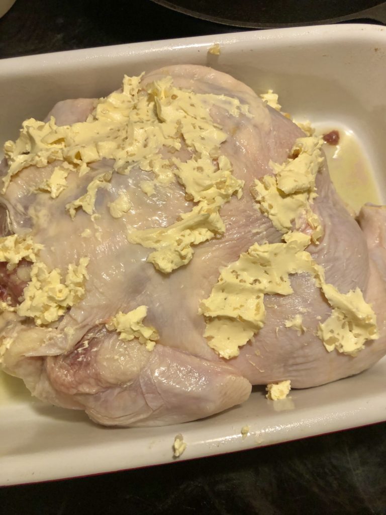 butter spread and minced garlic mixture over the top of whole roaster chicken