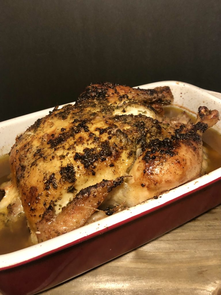 lemony whole oven roasted chicken in red roast pan resting