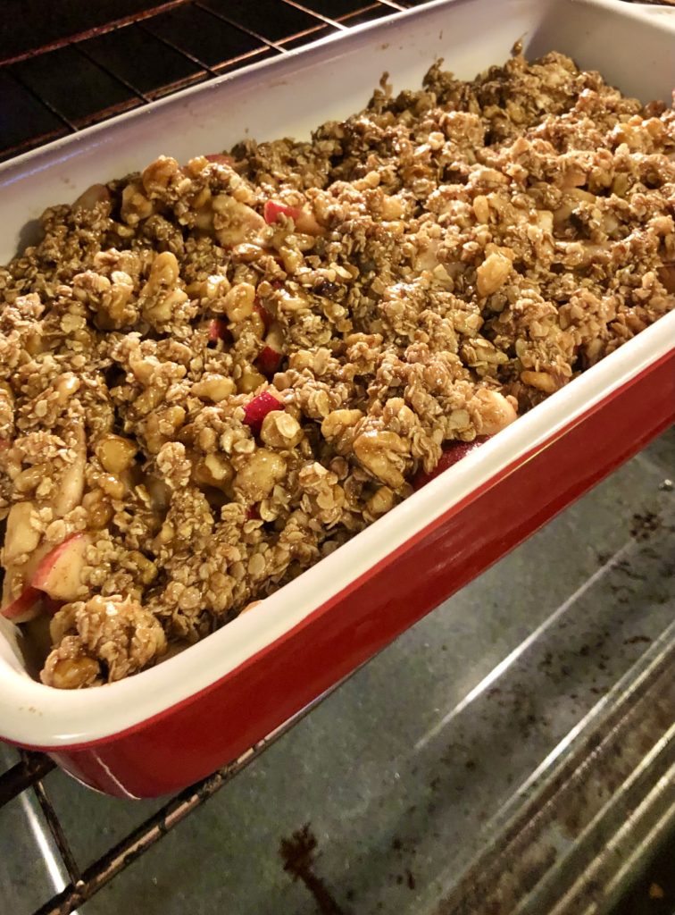 apple crisp in red baking dish going into the oven