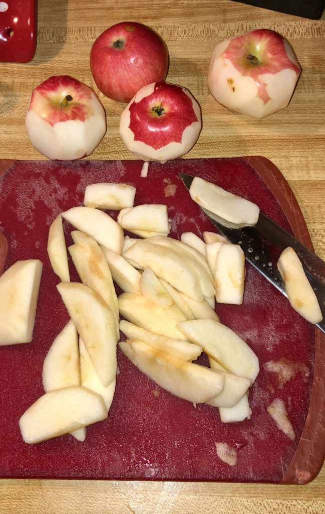 peeling and slicing red apples on red cutting board