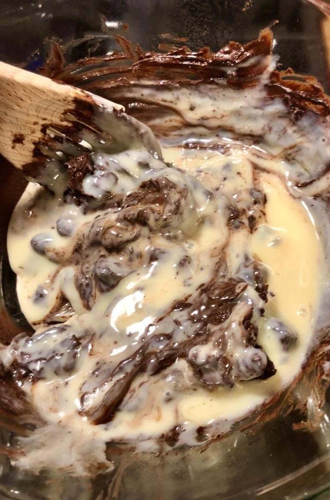 stirring melting chocolate with sweetened condensed milk with wooden spoon in double boiler