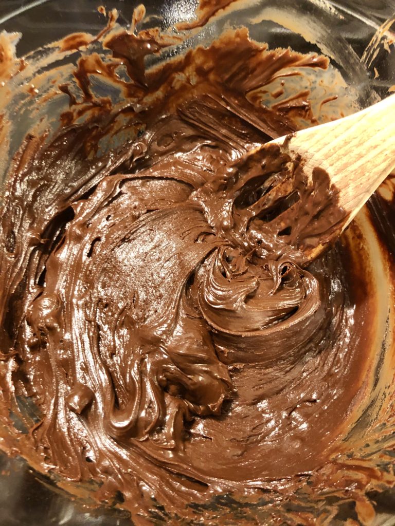 stirring chocolate fudge in glass bowl double boiler with wooden spoon