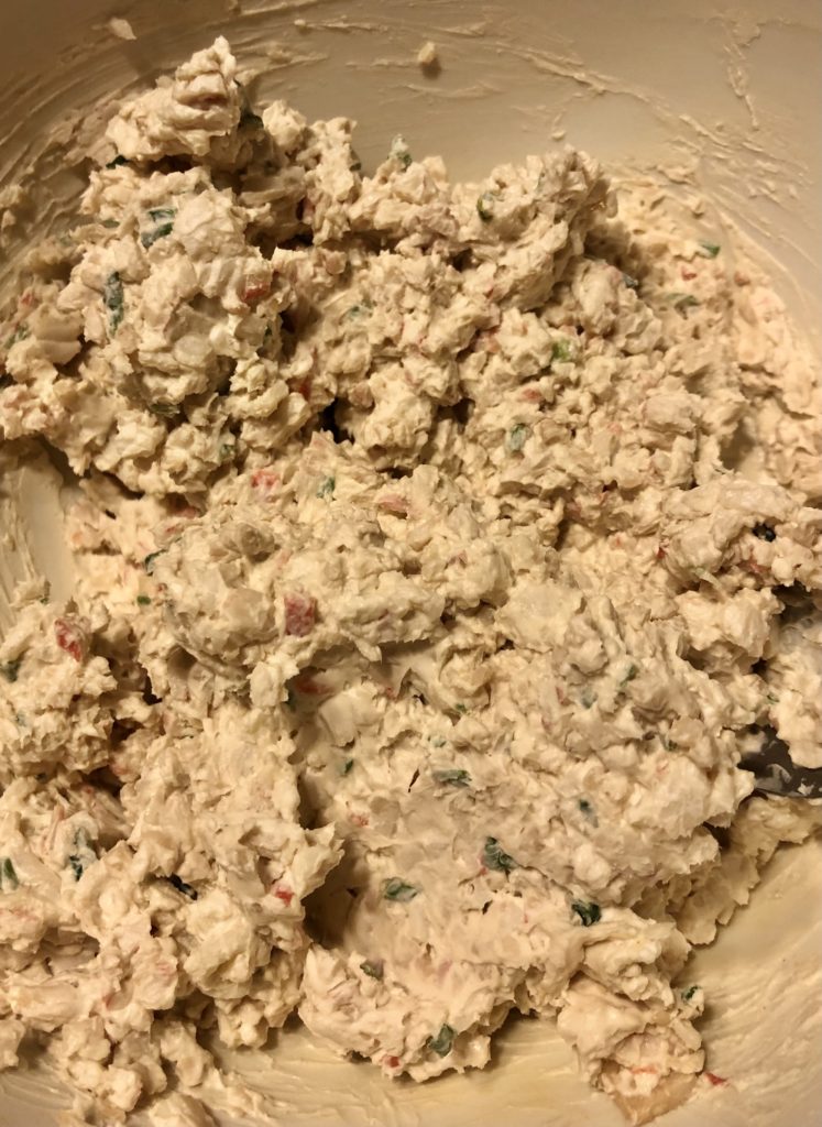 mashed together crab rangoon filling in white mixing bowl. cream cheese, imitation crab meat, soy sauce and green onion are mashed together