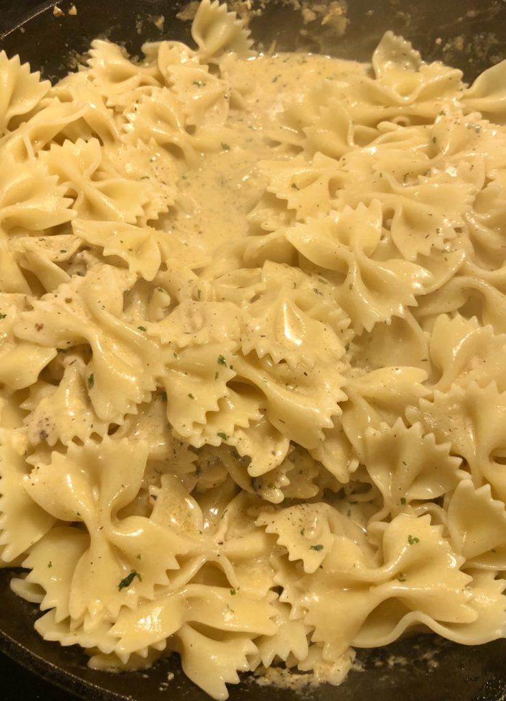 adding farfalle pasta to creamy cajun shrimp pasta sauce