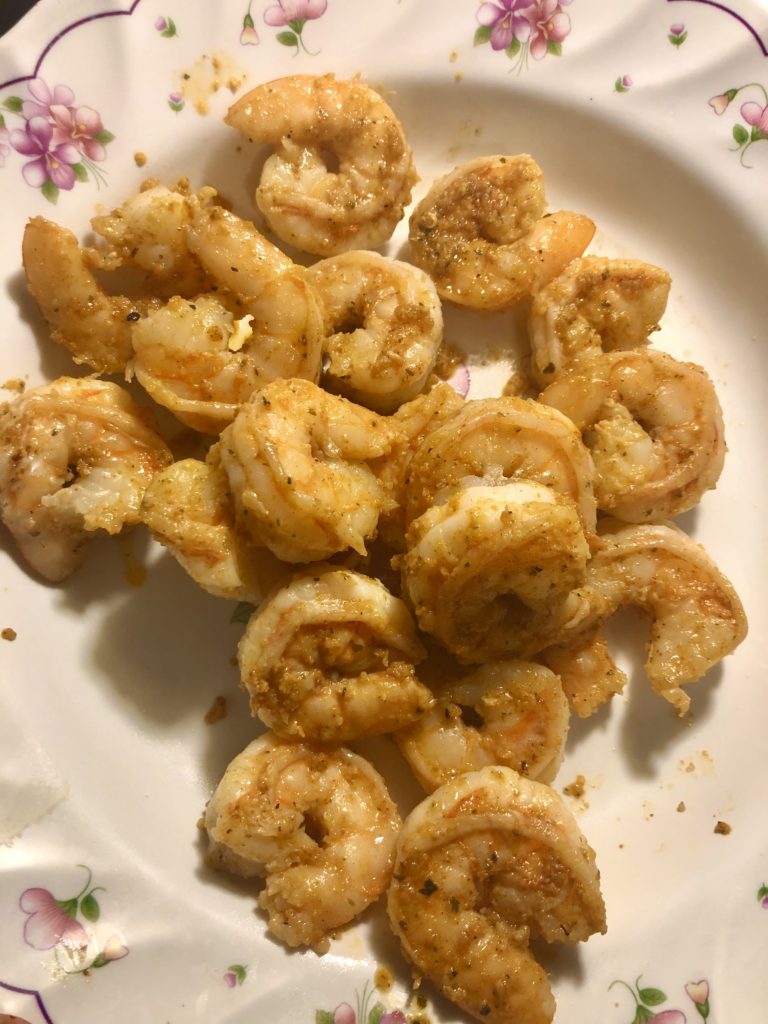 cajun shrimp that has been cooked. the shrimp has been transferred out of the pan and into a white floral bowl for later use.