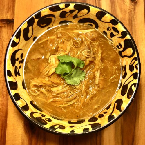 slow cooker curry chicken and sweet potato bone broth soup in leopard print bowl and garnished with cilantro in the middle. The bowl is on top of a wooden cutting board