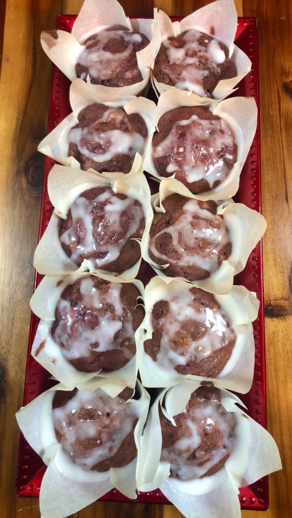 Ten strawberry bread muffins with lemon glaze pictured on red rectangular plate over wooden cutting board
