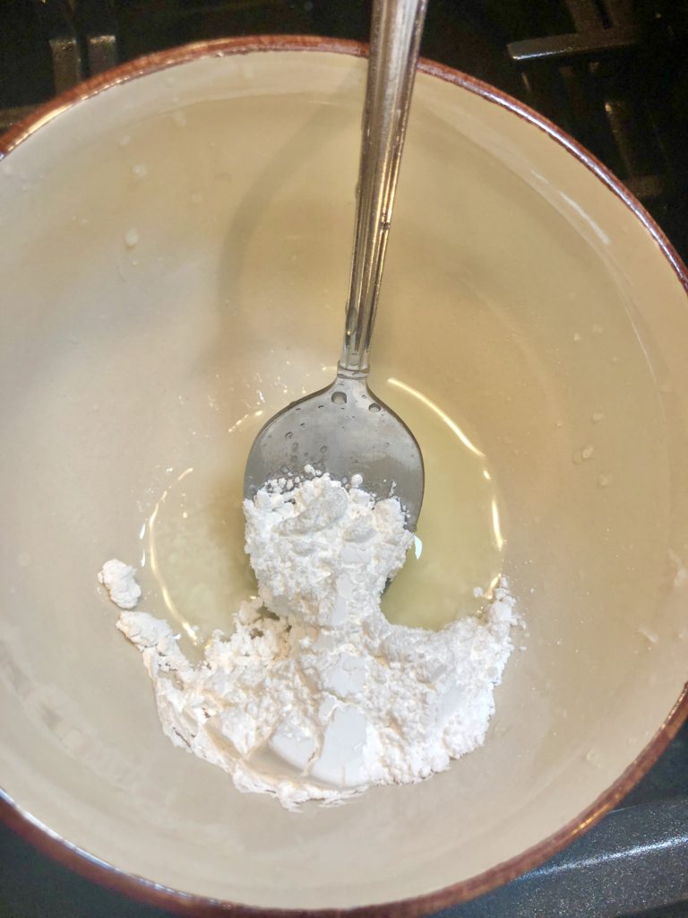 powdered sugar and fresh lemon juice in small bowl being stirred with silver spoon