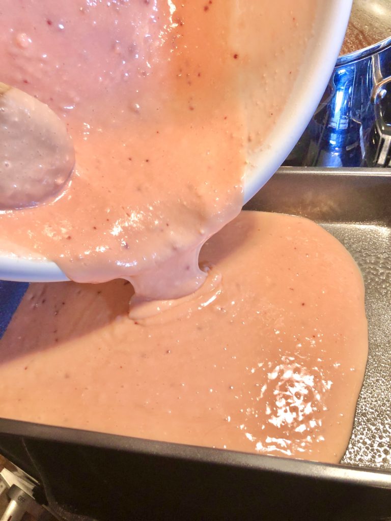 prepared strawberry cake mix being poured into greased 13x9 baking pan