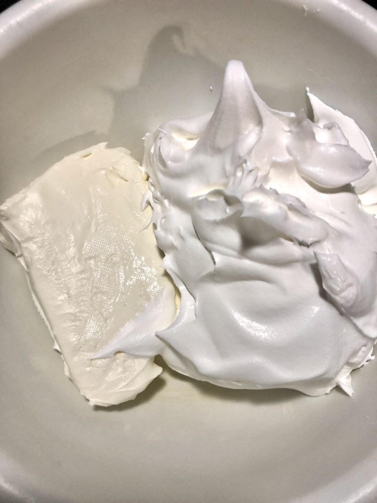 block of cream cheese and container of Cool Whip in medium white mixing bowl