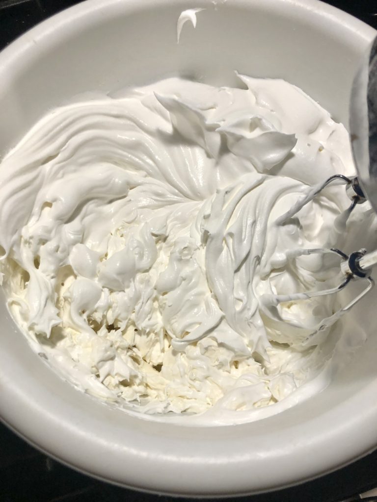 cream cheese and cool whip being beaten with an electric mixer