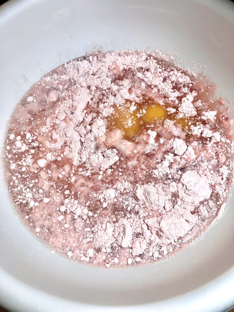 preparing strawberry box cake mix in large white mixing bowl with vegetable oil, eggs and water
