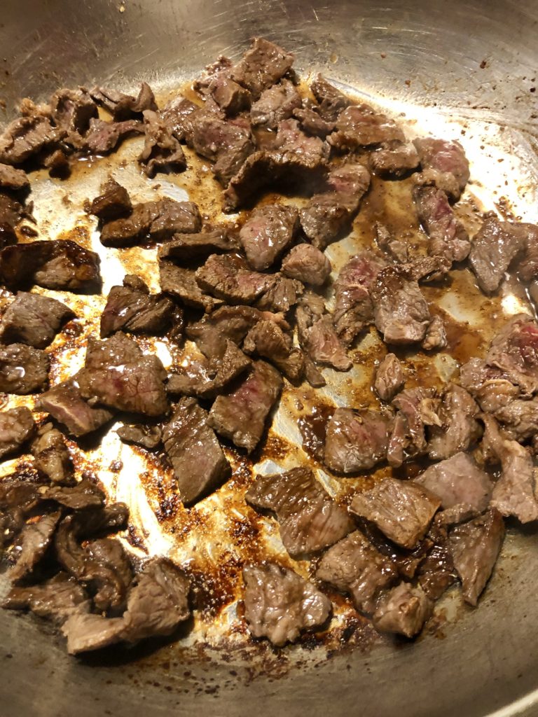 marinated Thai beef frying in large silver skillet