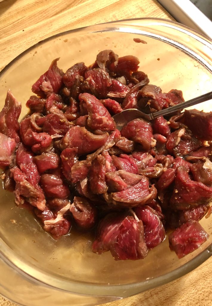 thinly sliced steak marinating in glass bowl