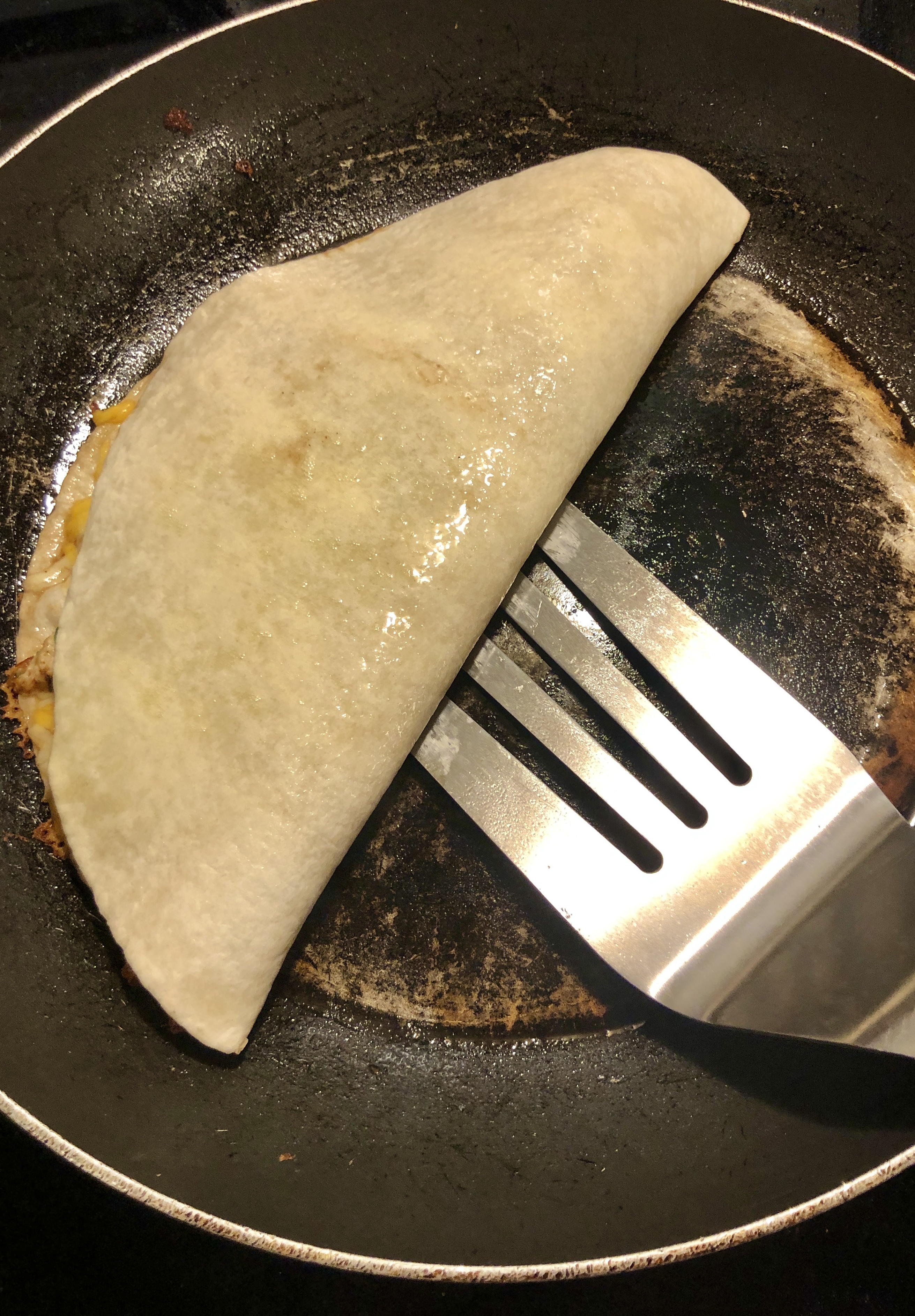 quesadilla being flipped in pan with large spatula