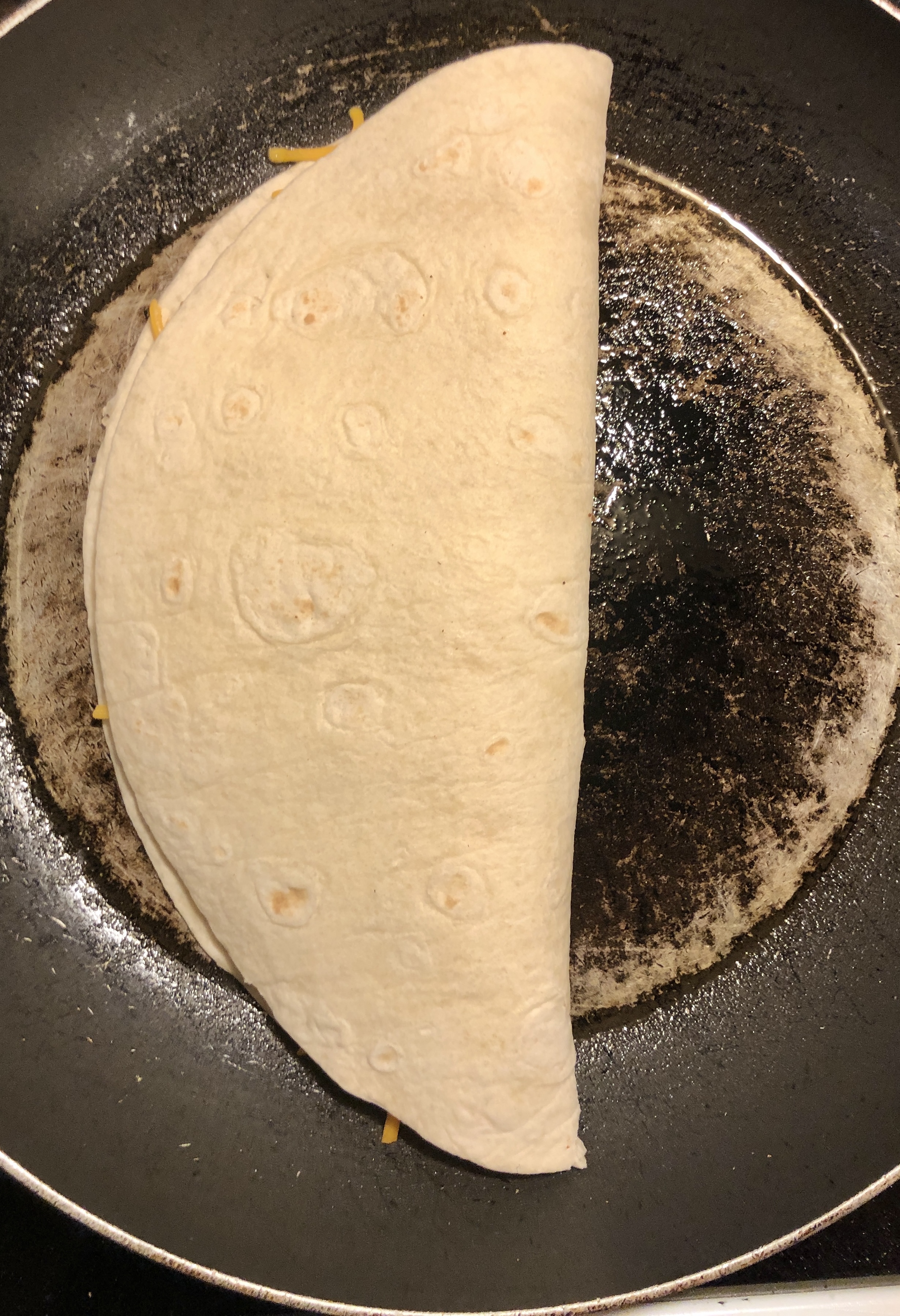 chicken quesadilla placed in pan to cook on first side