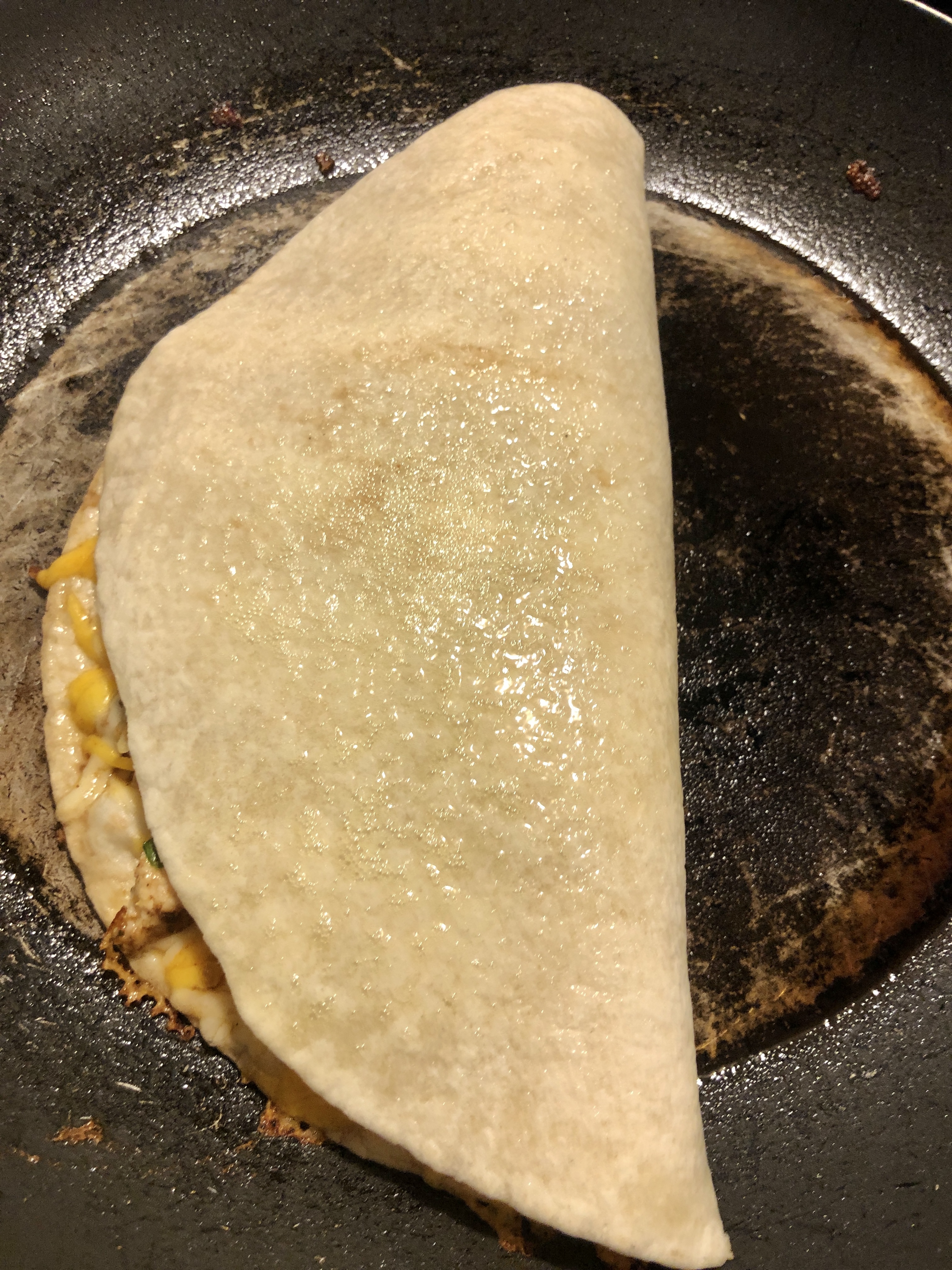 chicken quesadilla cooking in pan and sprayed with pan spray prior to flipping