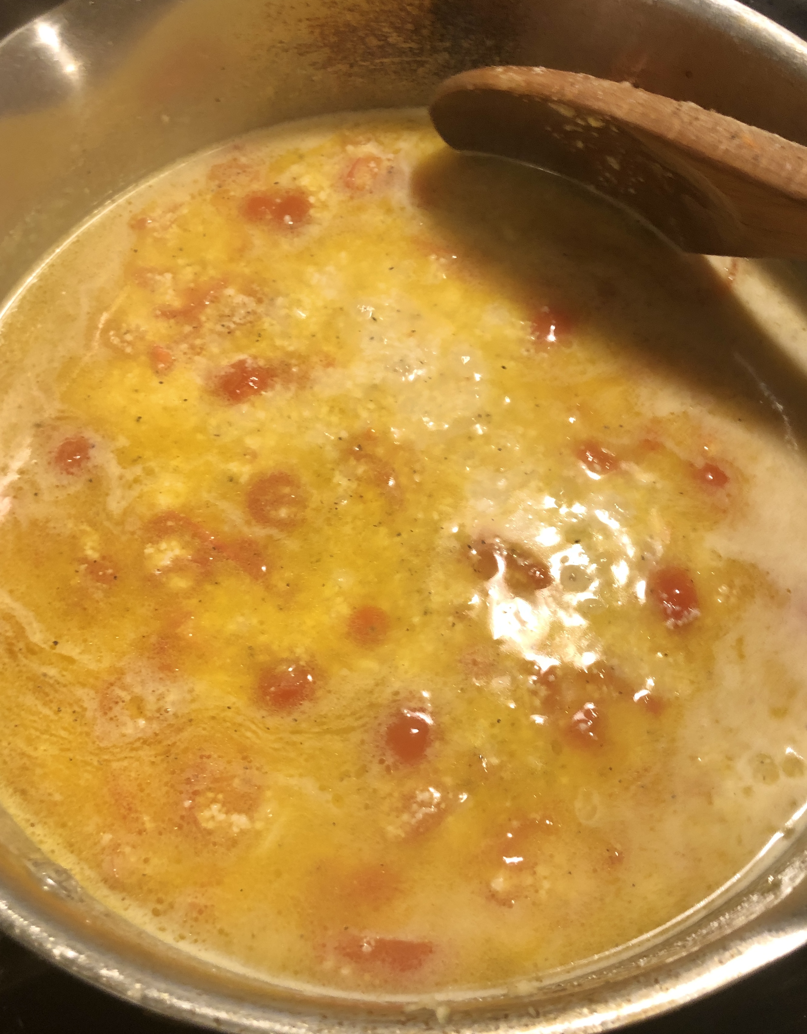 Lemon parmesan sauce with cherry tomatoes in saucepan.
