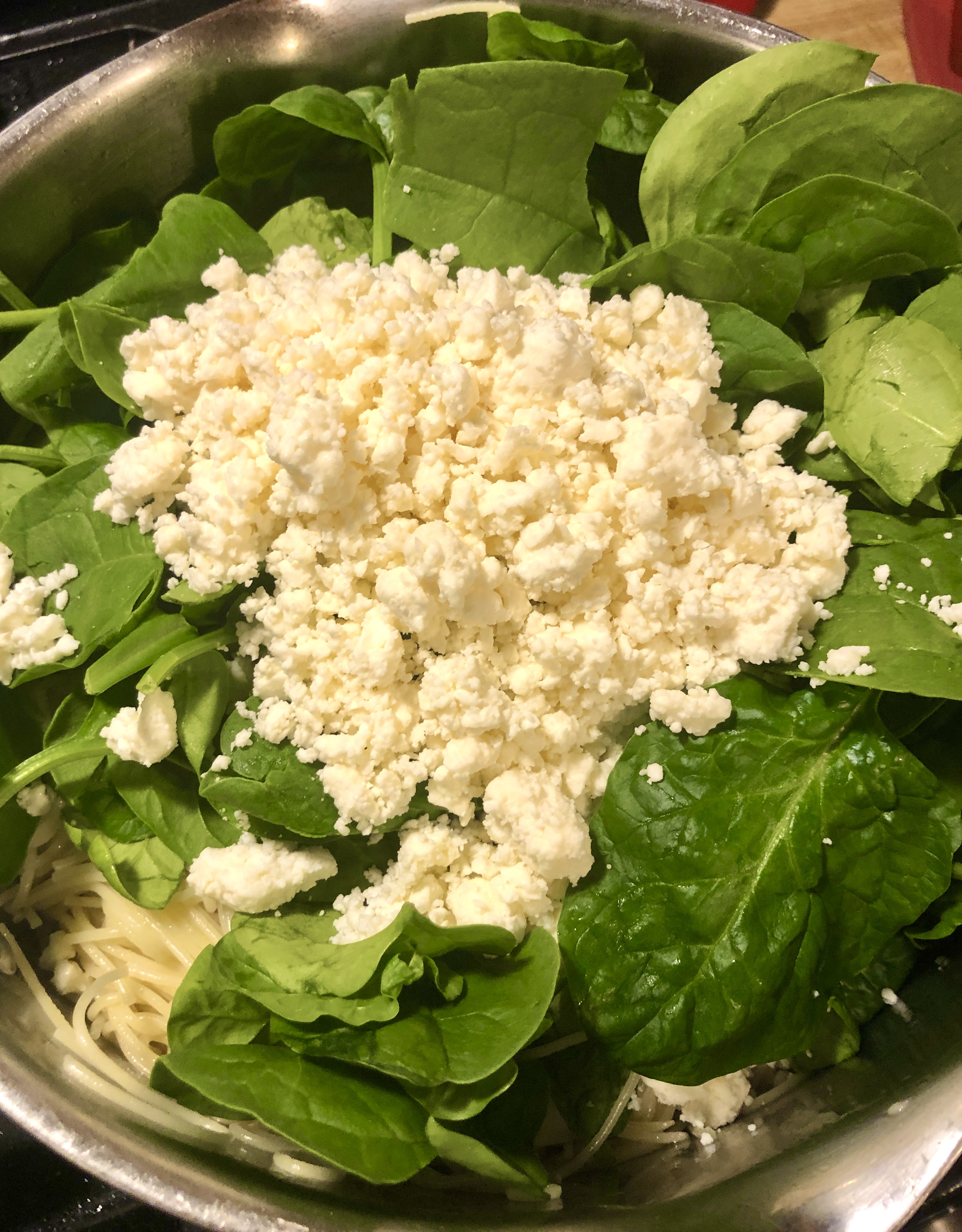 Spinach and feta cheese in pot over fettuccine.