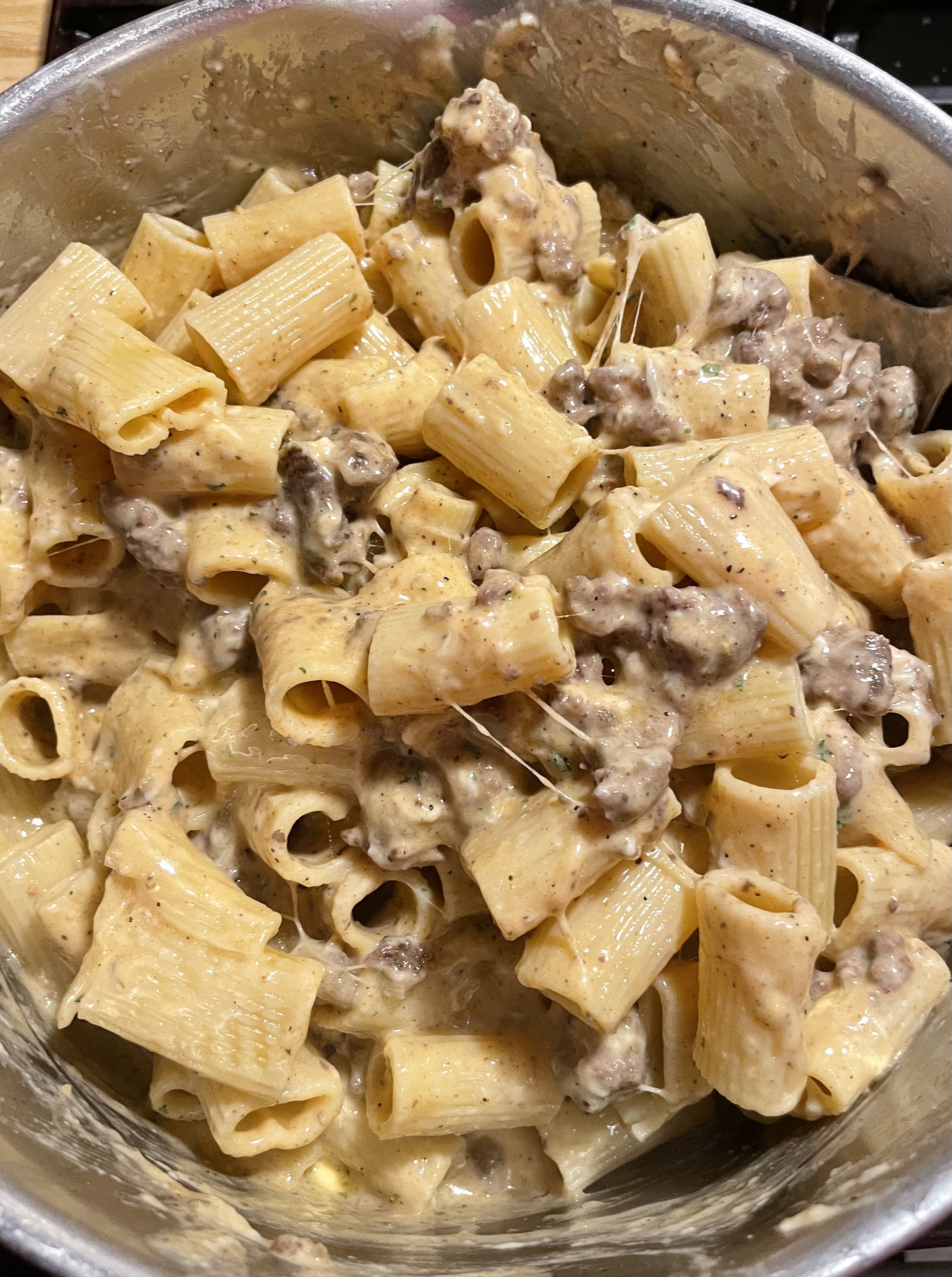 Homemade Hamburger Helper being stirred together completely with the ground beef, pasta and cheese sauce.