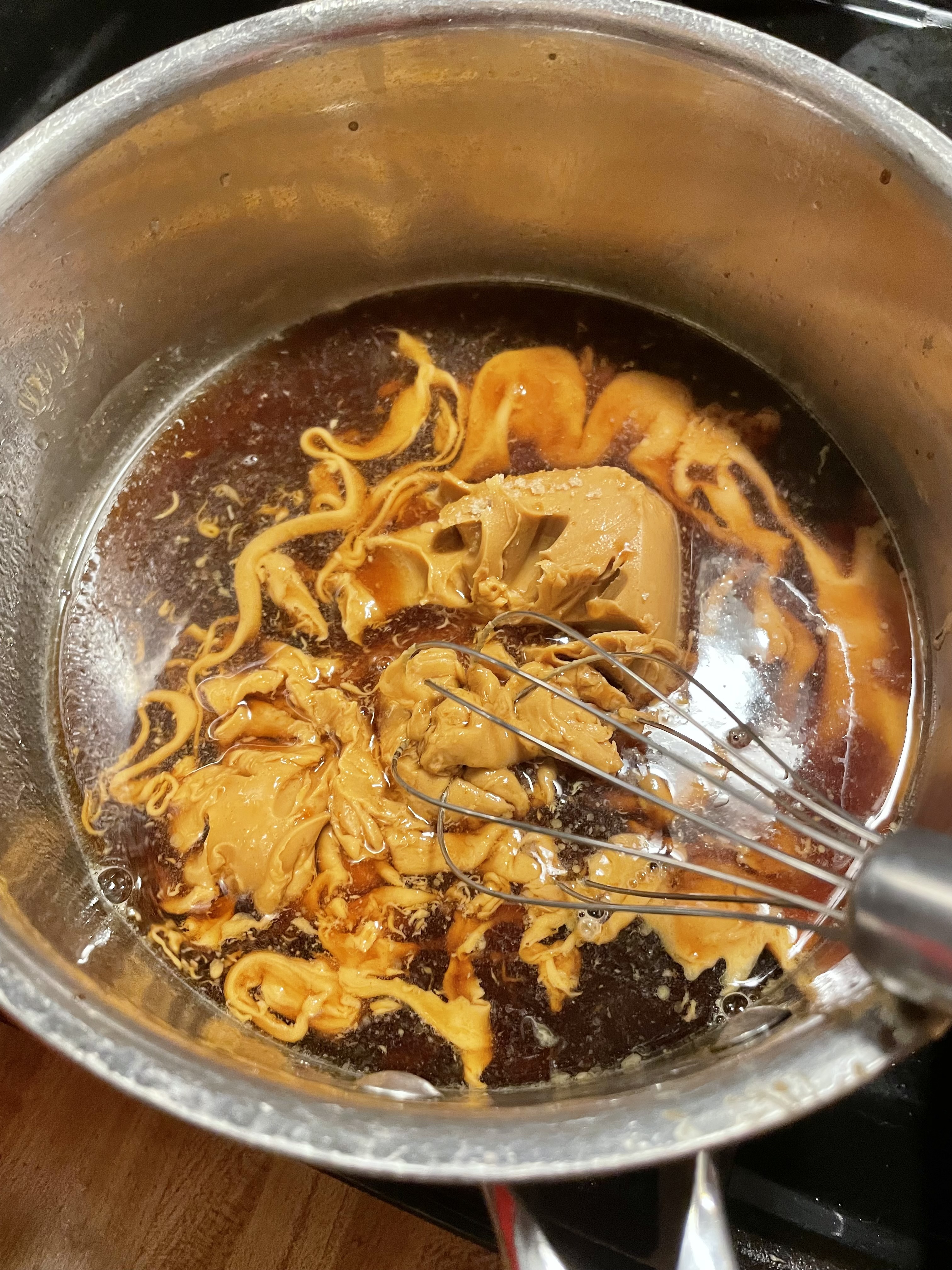 Peanut sauce ingredients in medium saucepan with whisk.