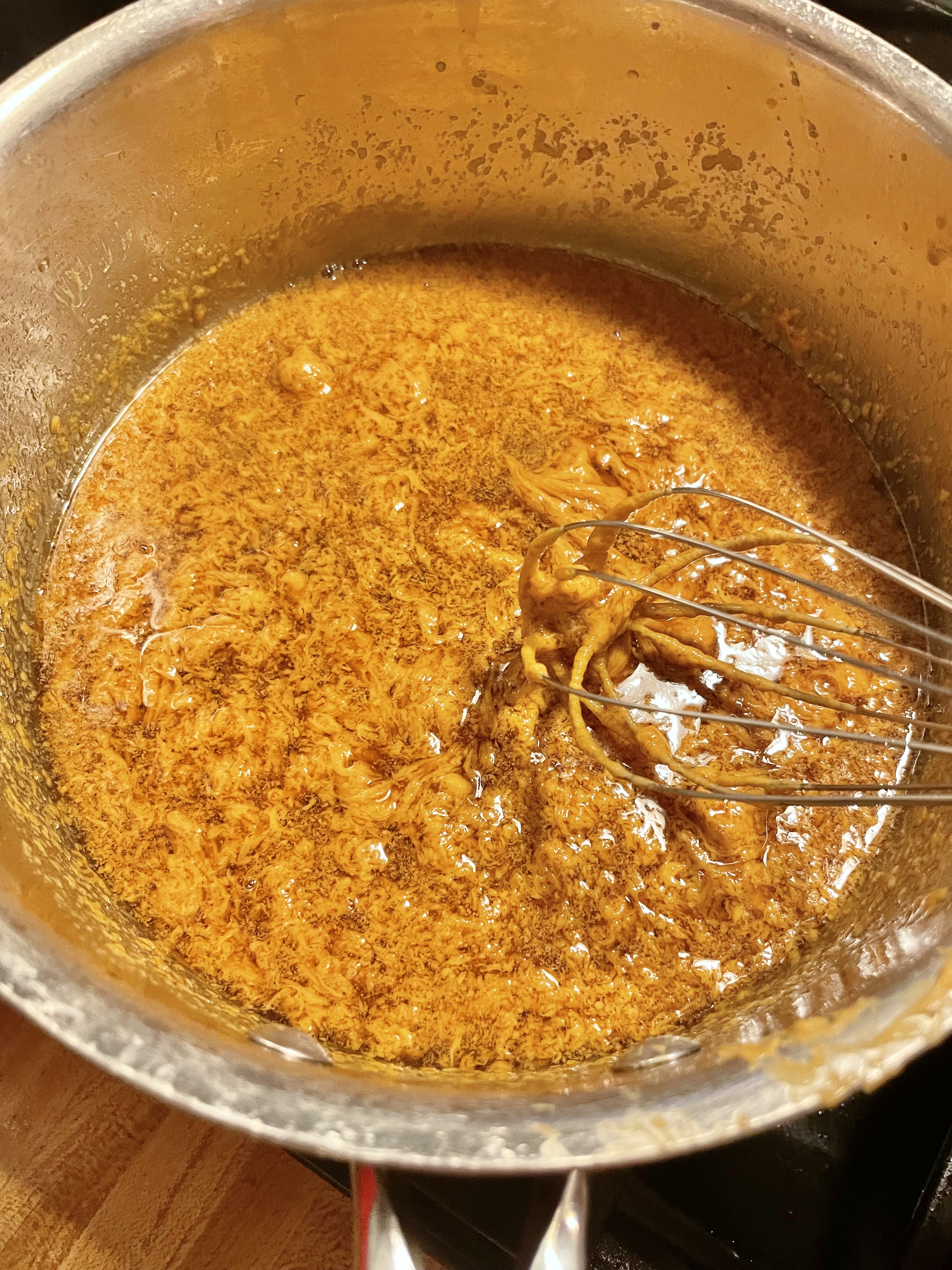 Peanut sauce being whisked in saucepan.