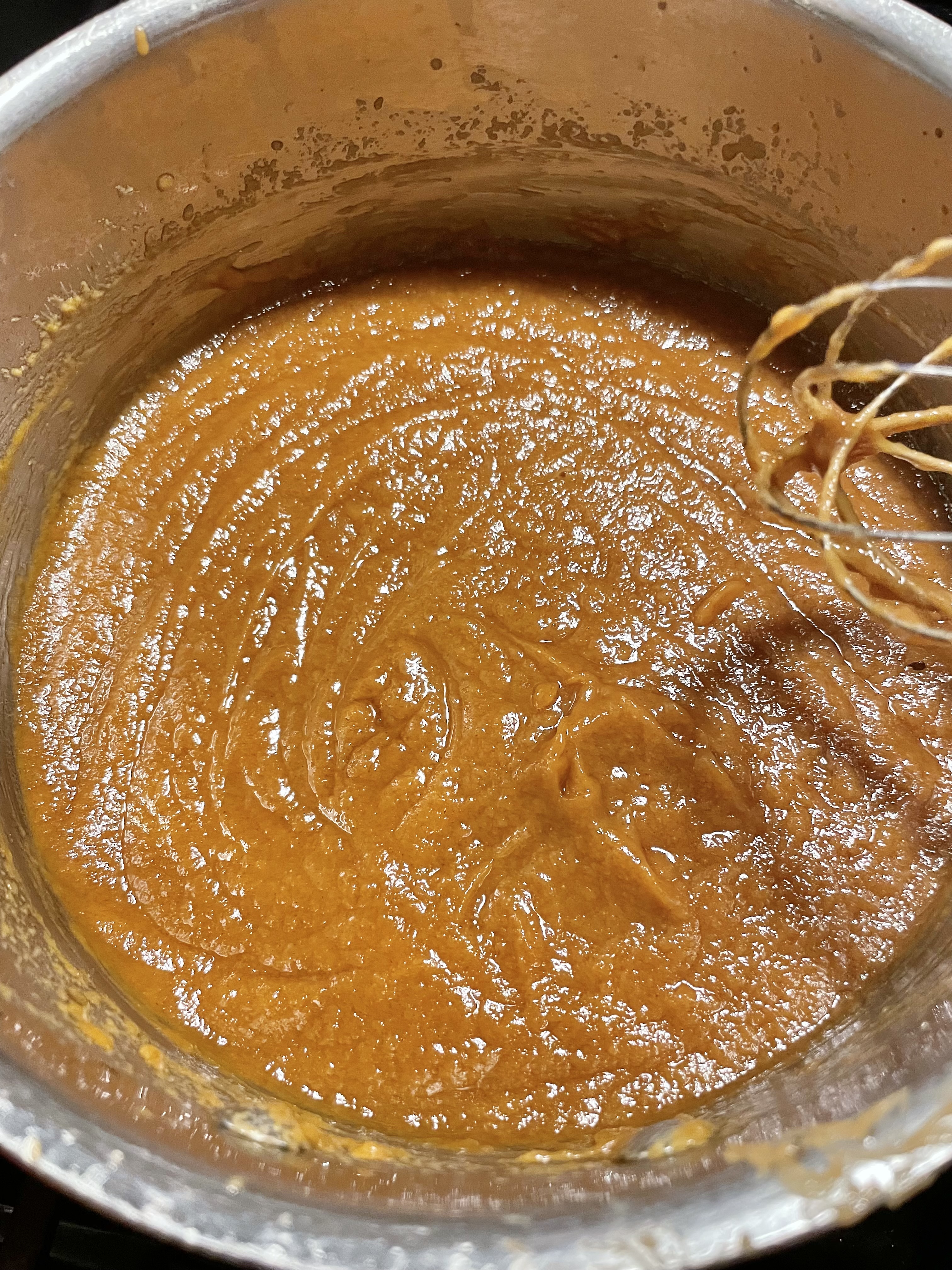 Smooth peanut sauce in saucepan with whisk.