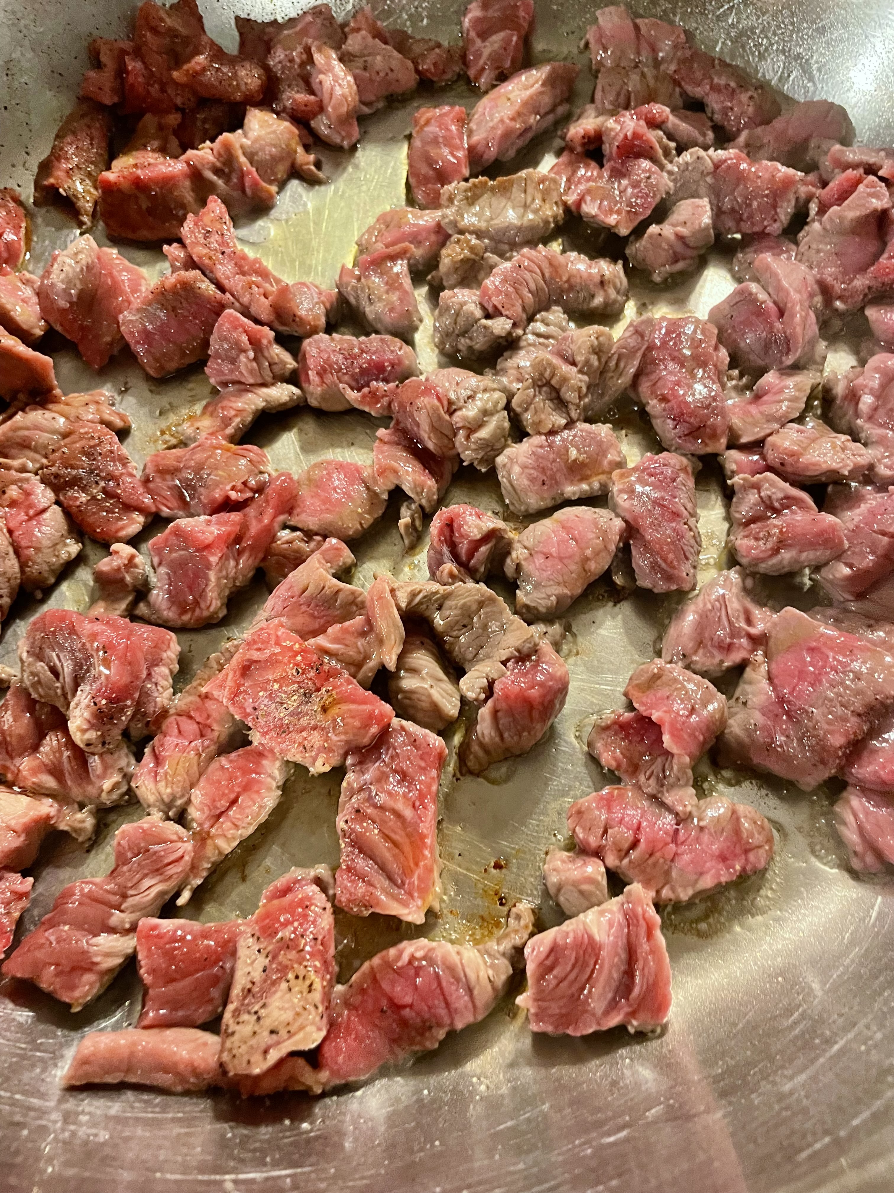 Thinly sliced Angus steak cooking in a skillet.