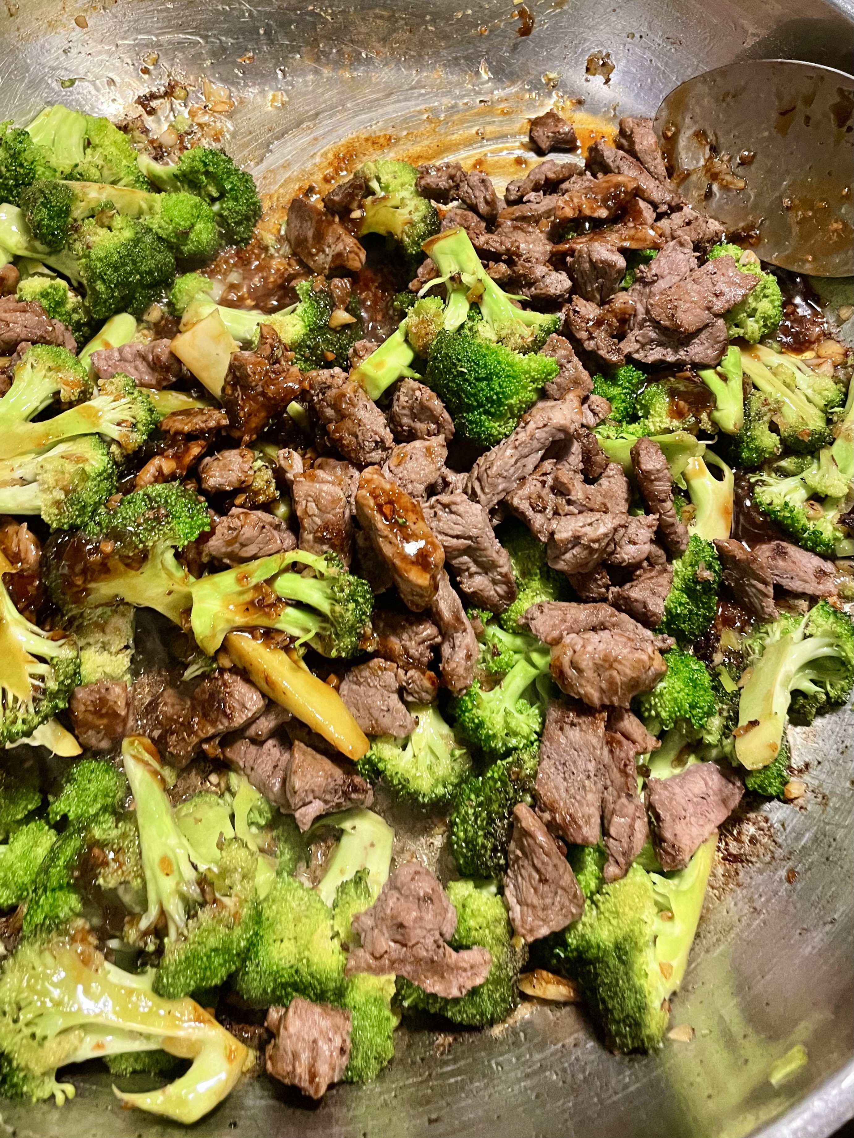 Stirring beef and broccoli ingredients together with sauce in skillet.