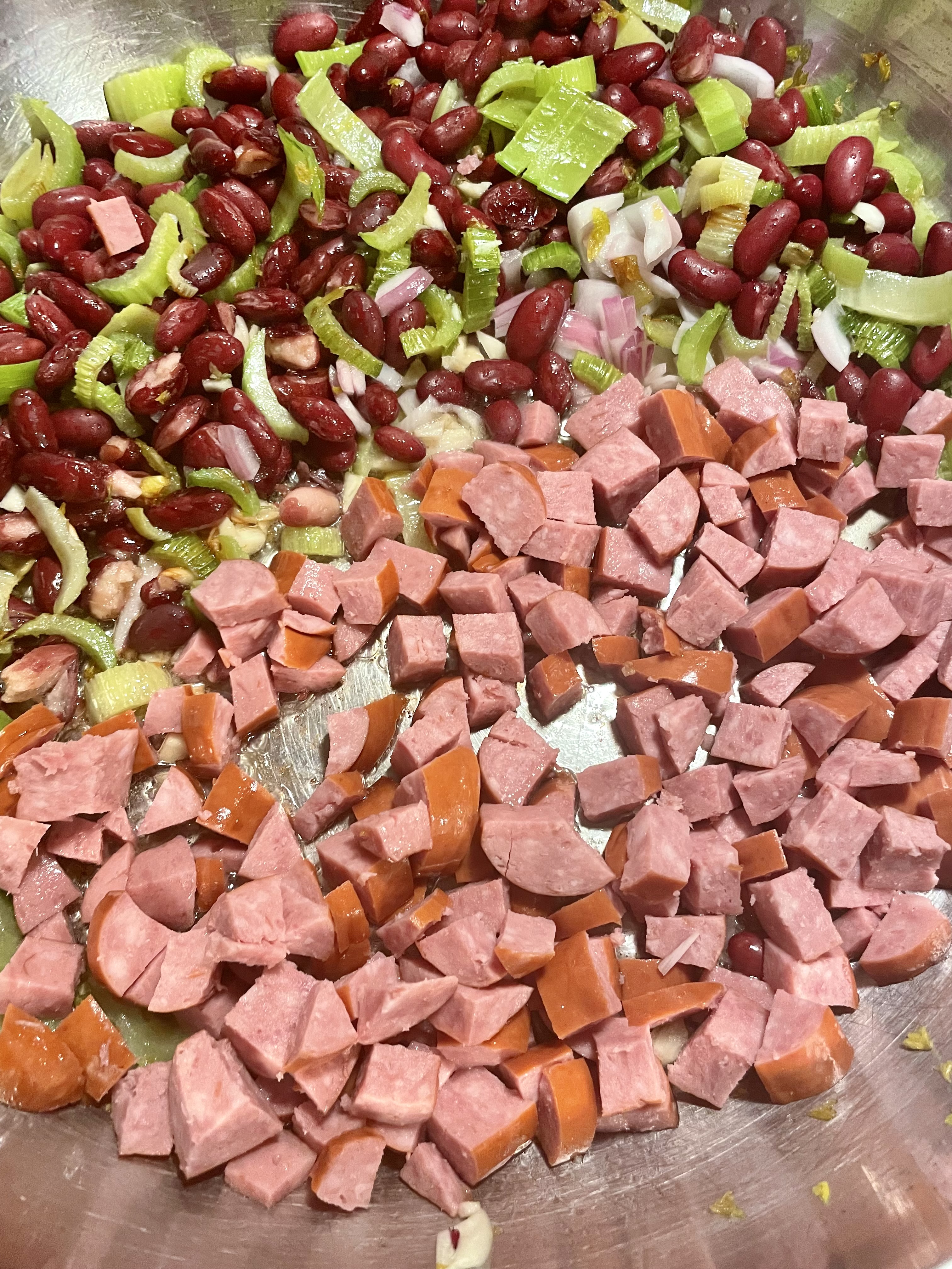 Kielbasa, red beans, celery, garlic and onion cooking in skillet.