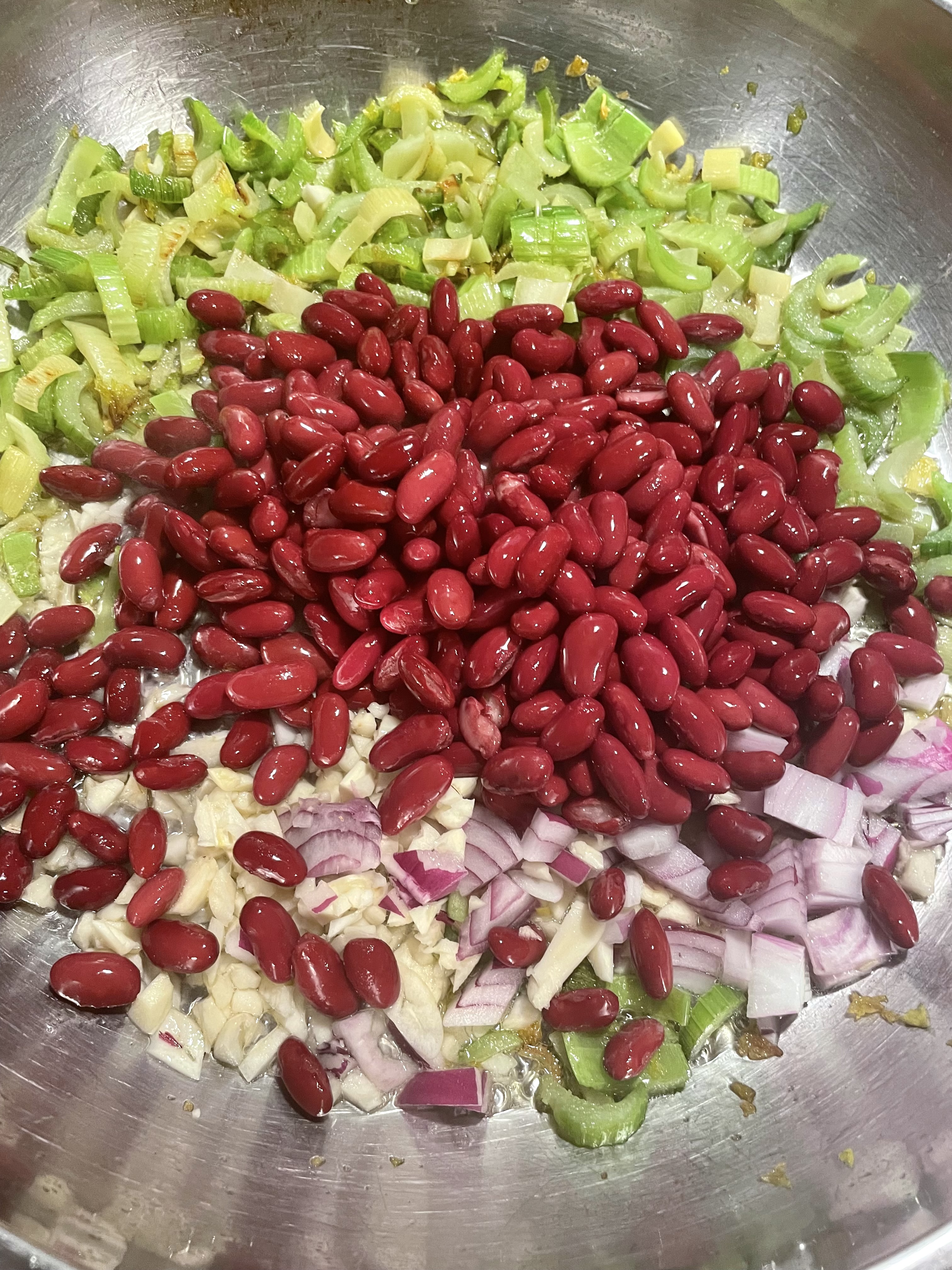 Skillet cooking celery, garlic, onion and red beans.