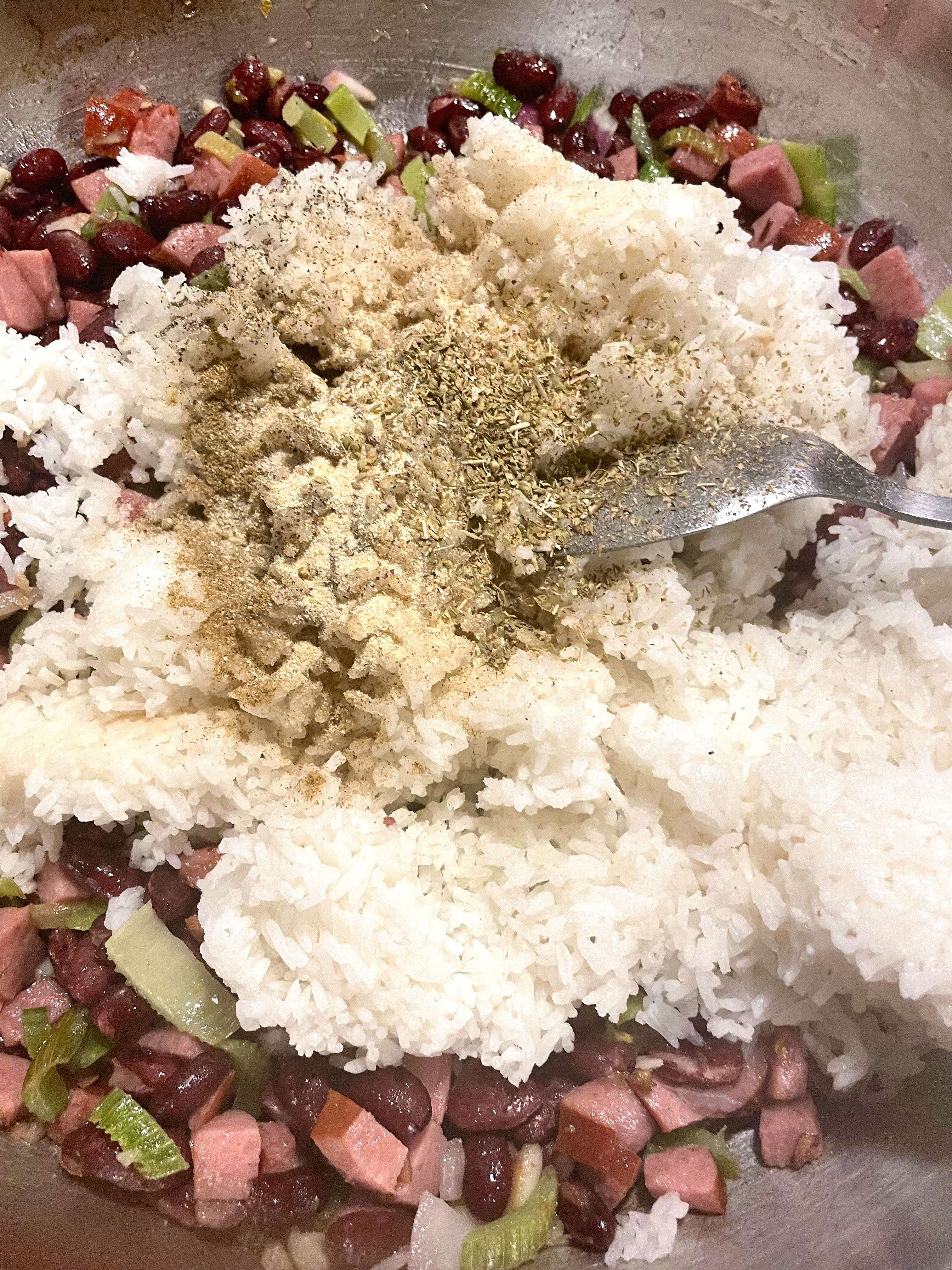 White rice and seasonings added to skillet cooking kielbasa and red beans.