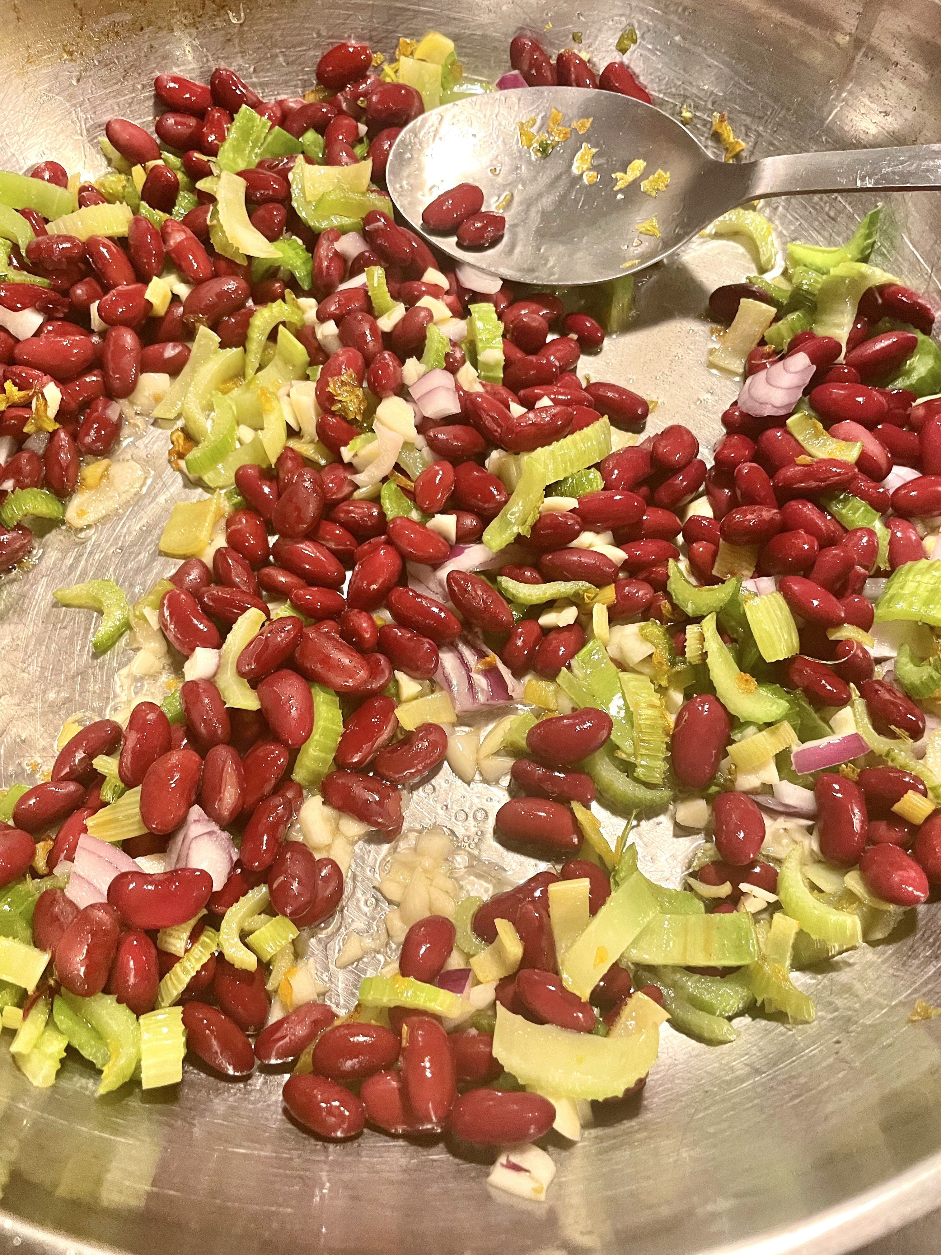 Stirring celery, red beans, garlic and onion in large skillet while cooking.