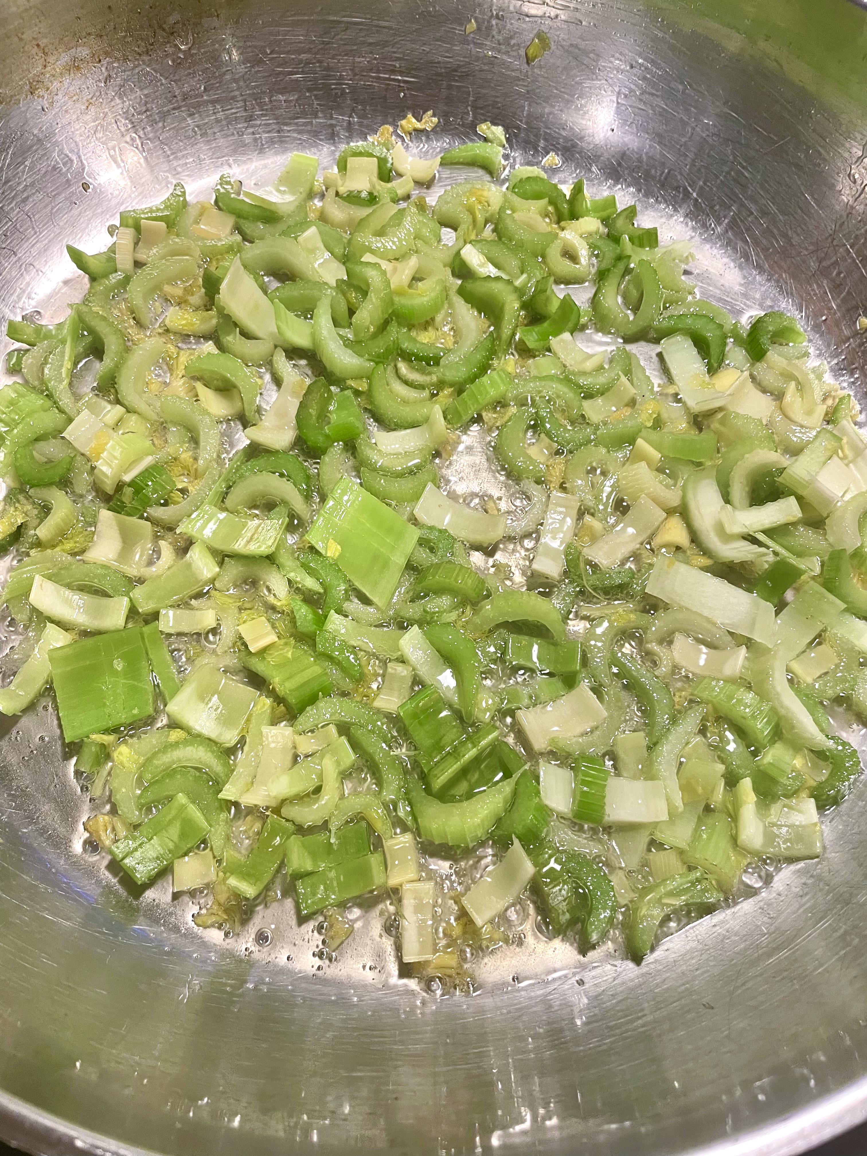 Cooking thinly sliced celery in large skillet with vegetable oil.