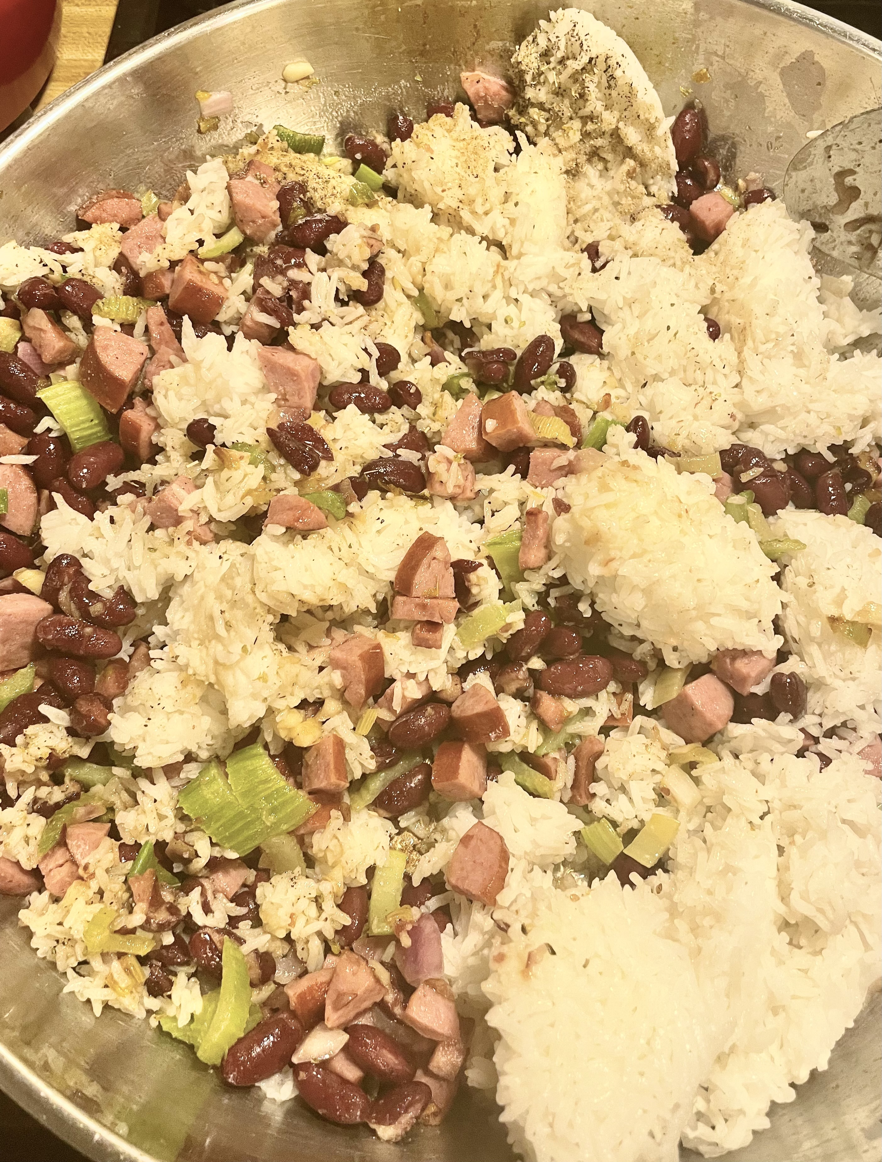 Stirring kielbasa, celery and red beans with white rice and seasonings in large skillet.