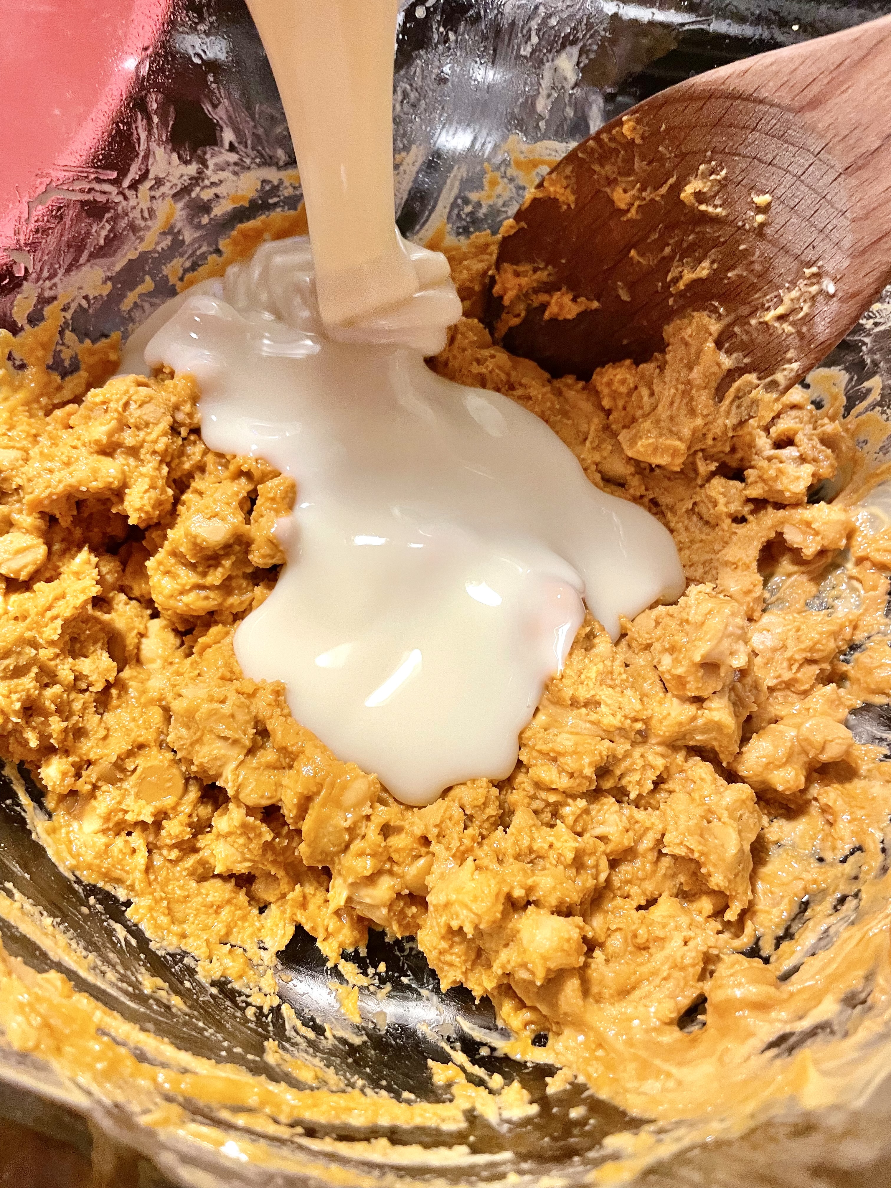 Sweetened condensed milk being poured into a double boiler with melted butterscotch chips. 