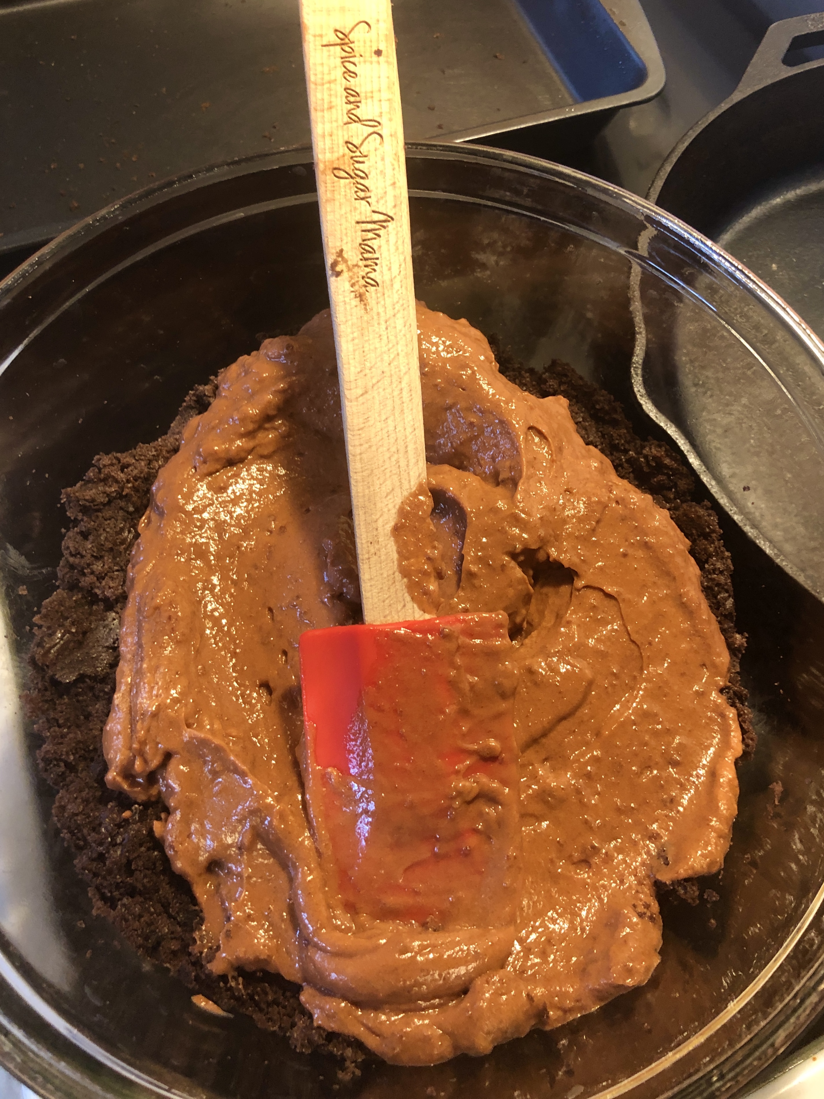 Adding and spreading chocolate pudding over chocolate cake in trifle bowl.