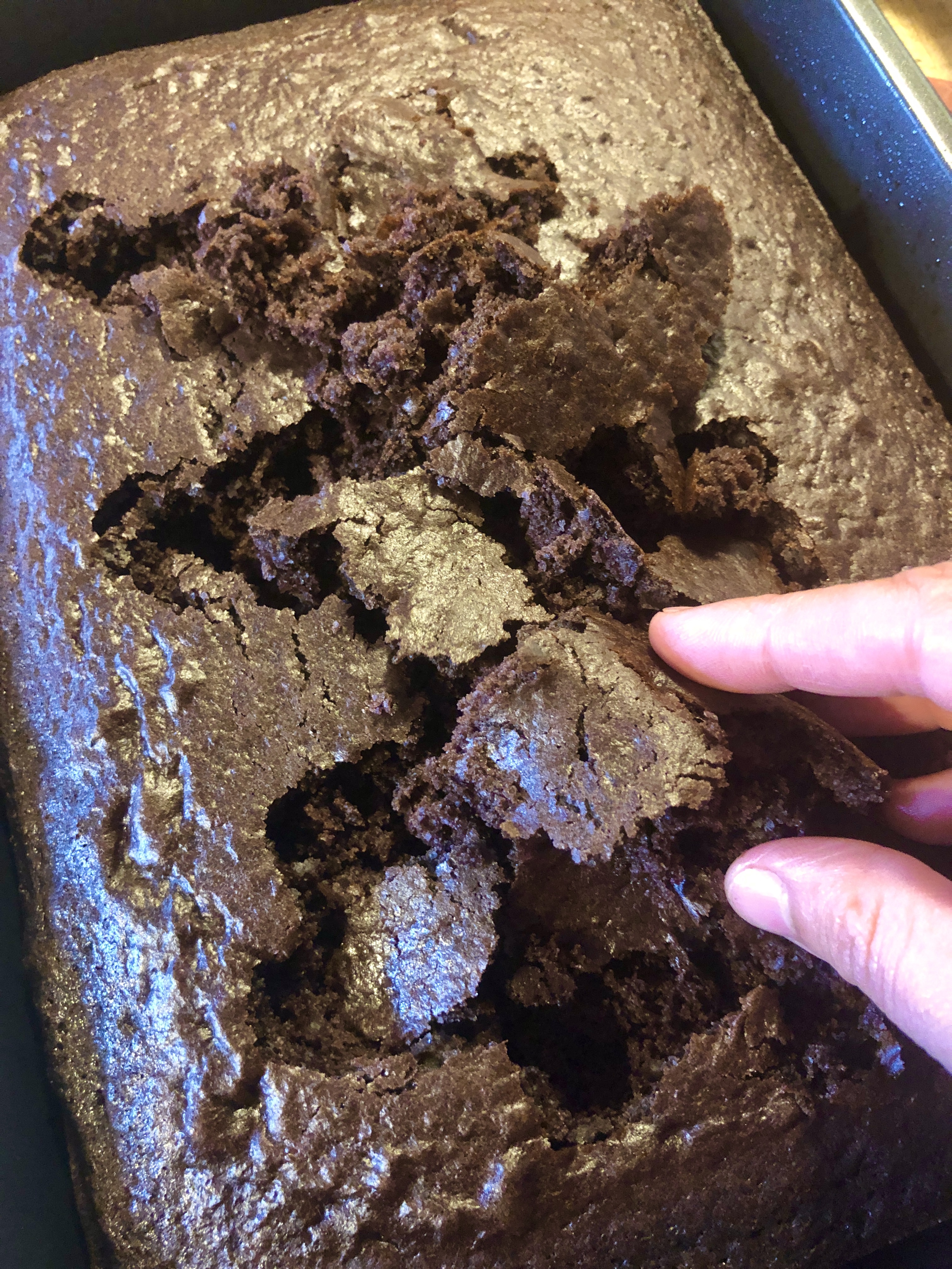 Breaking apart cooled chocolate box cake in 13x9 pan.