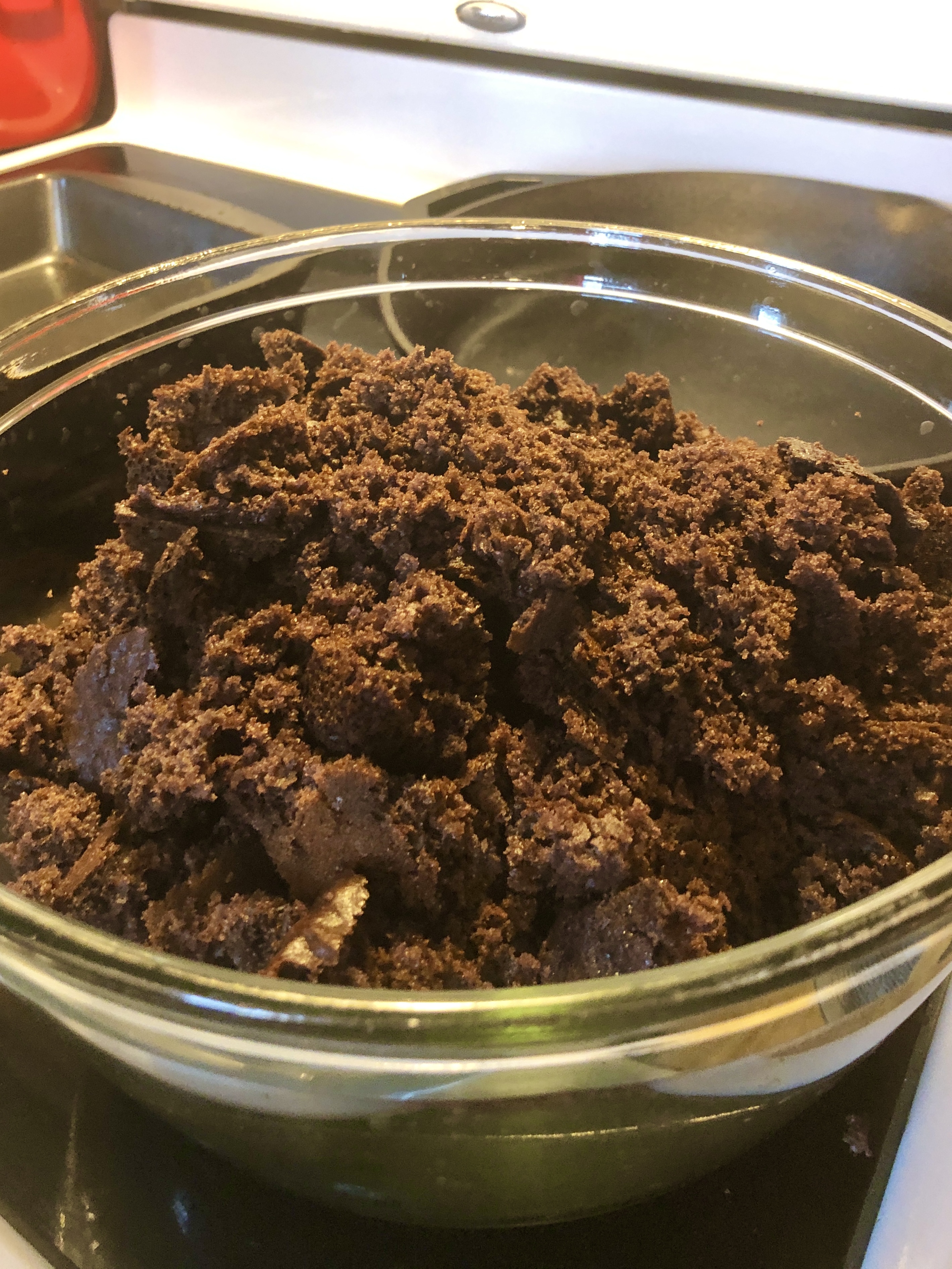 Adding broken apart chocolate cake into trifle bowl.