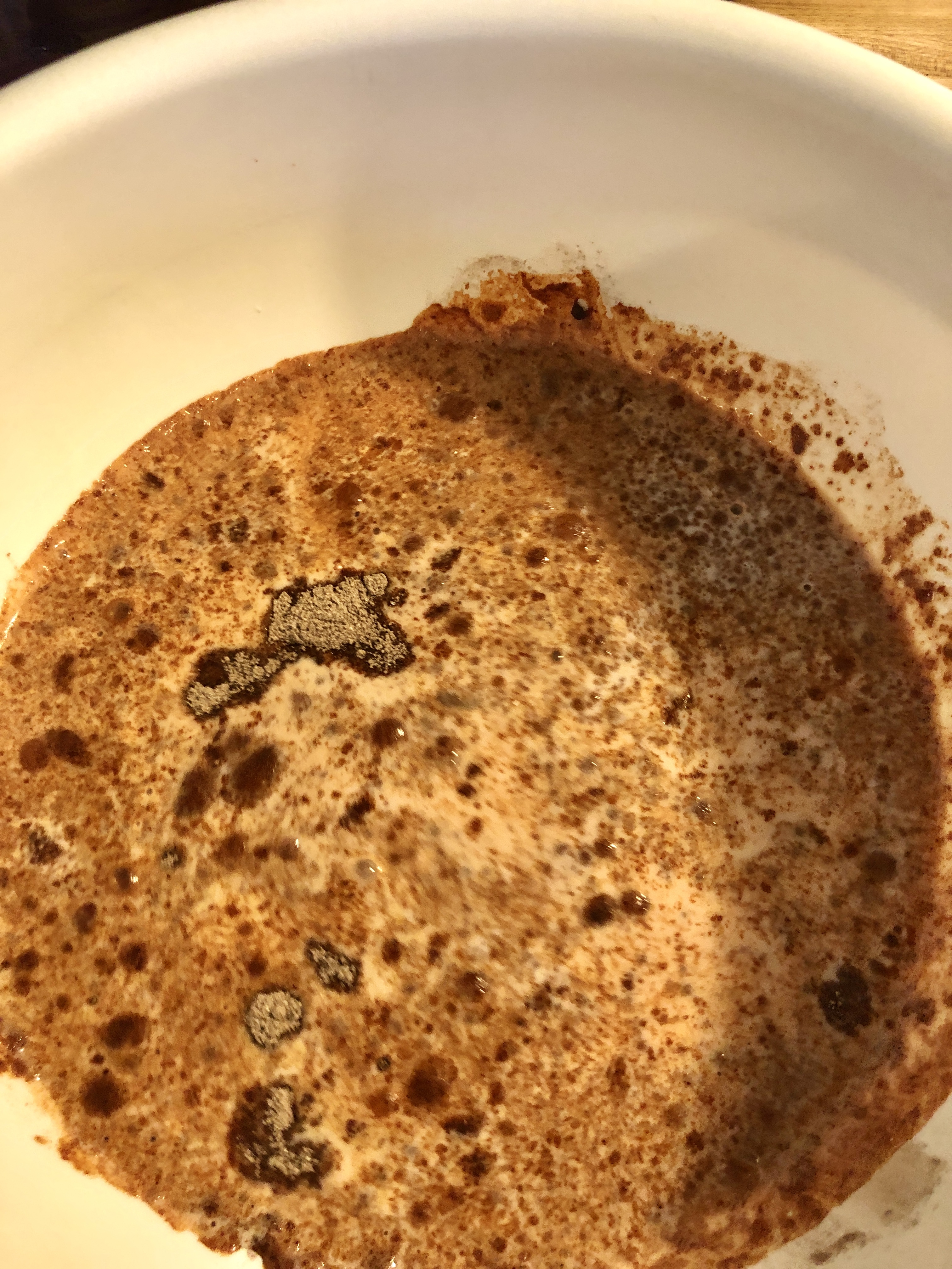 Instant chocolate pudding mix and milk in white mixing bowl.