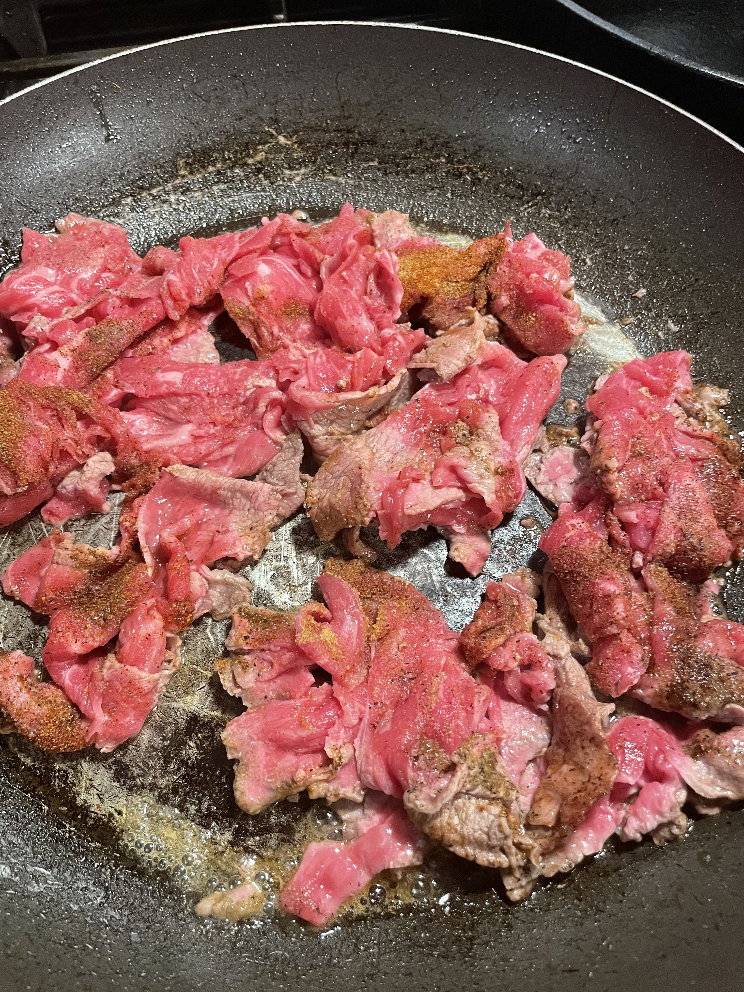 Shaved steak added to large frying pan.