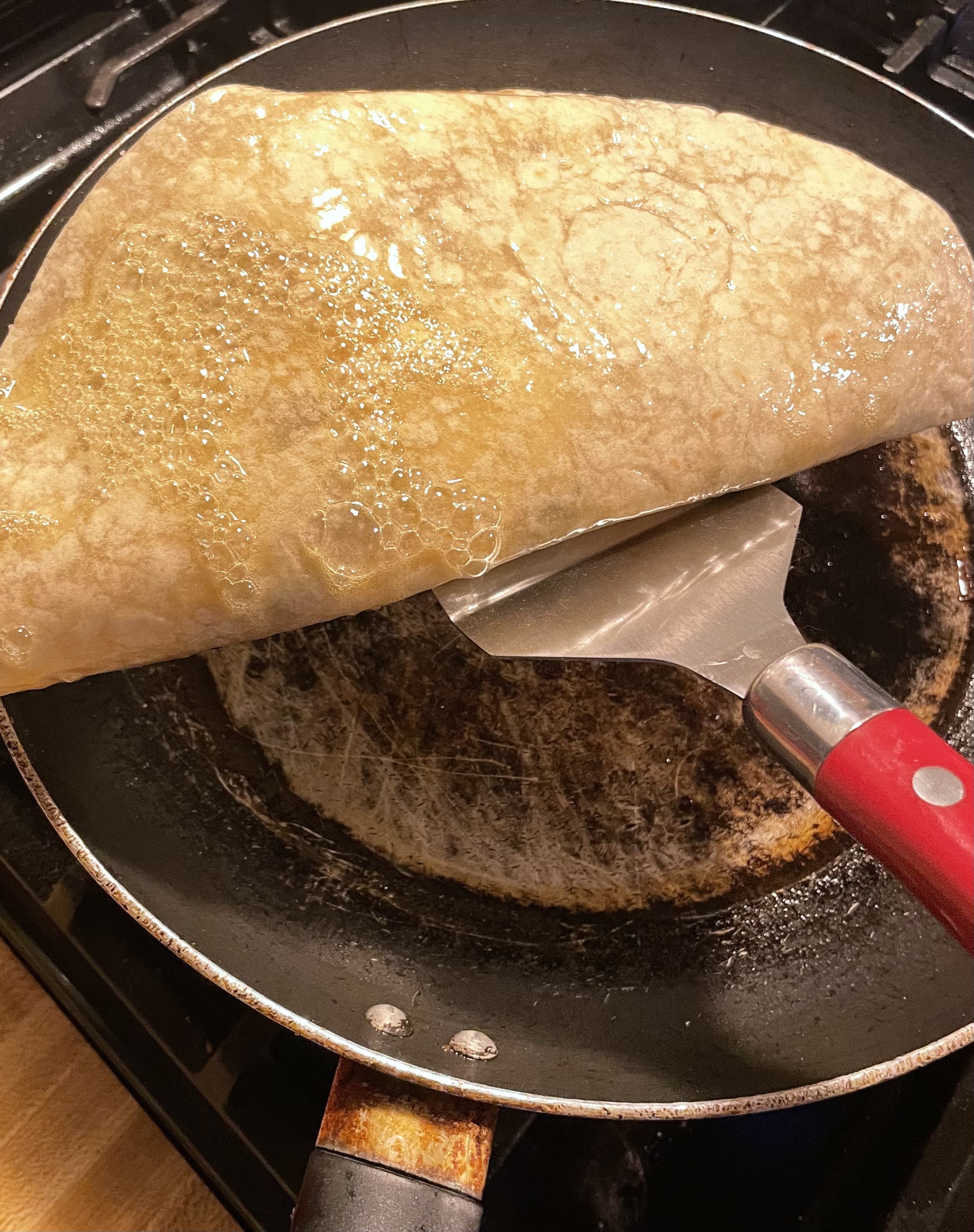 Flipping a quesadilla that has had the top pan sprayed.
