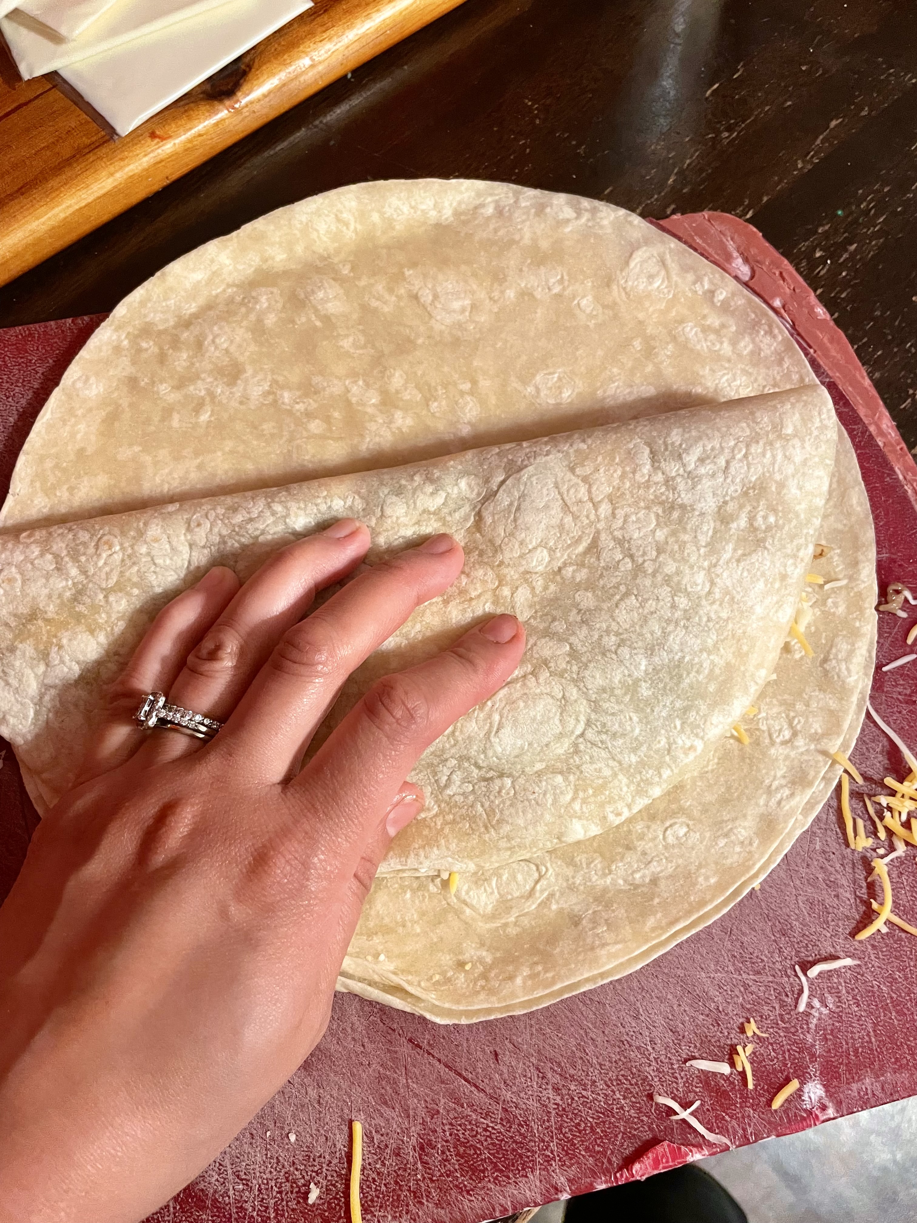 Folding over the other half of a flour tortilla to make a quesadilla.