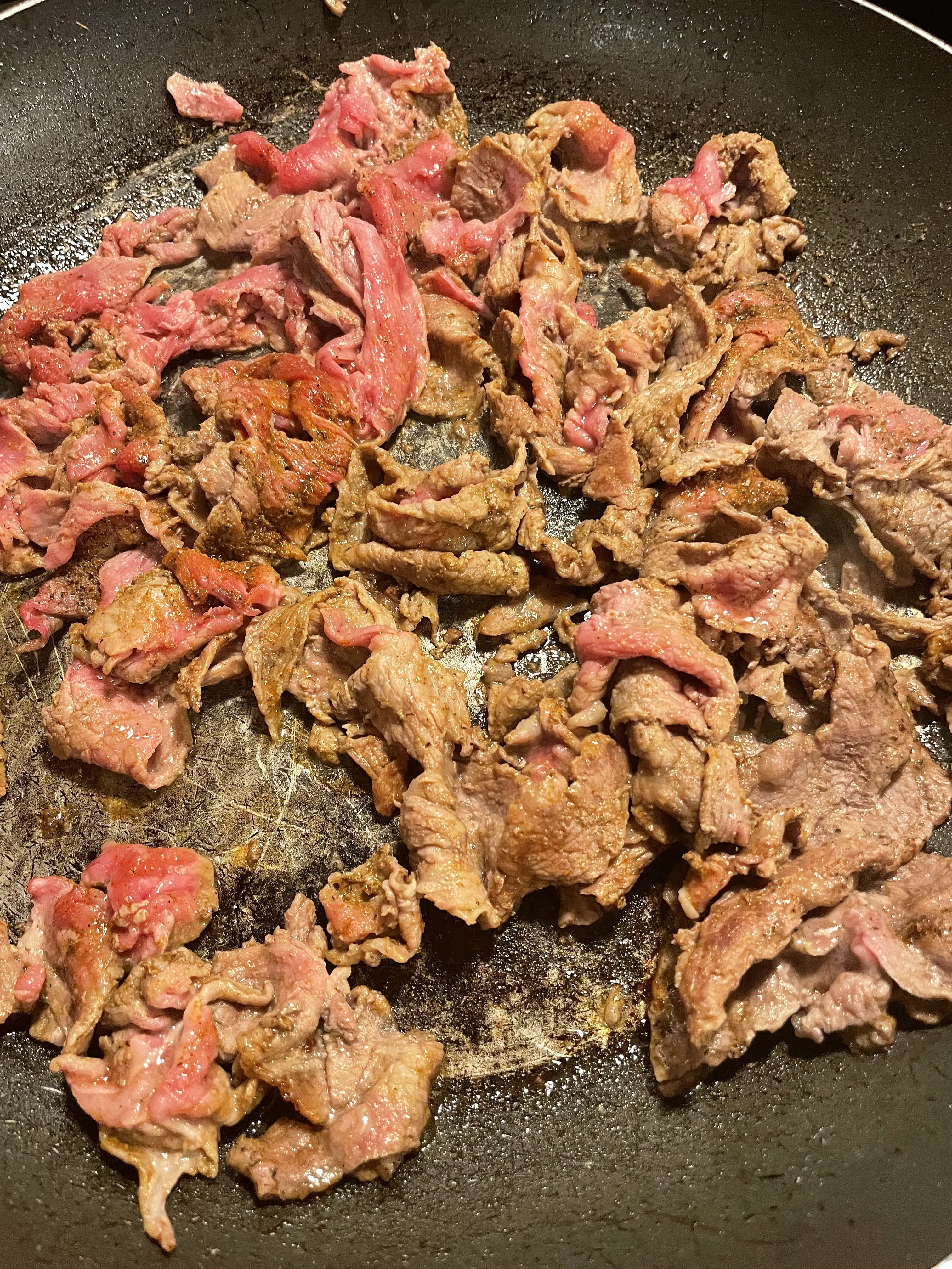 Shaved steak frying in pan.