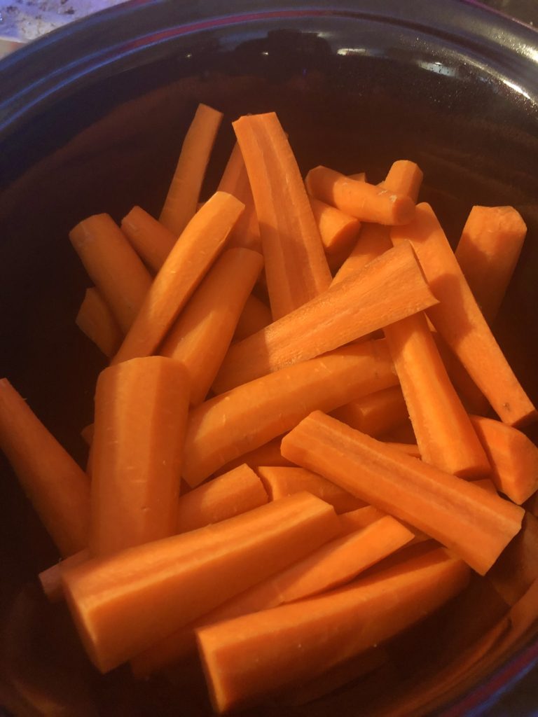 Sliced and peeled whole carrots in a slow cooker.
