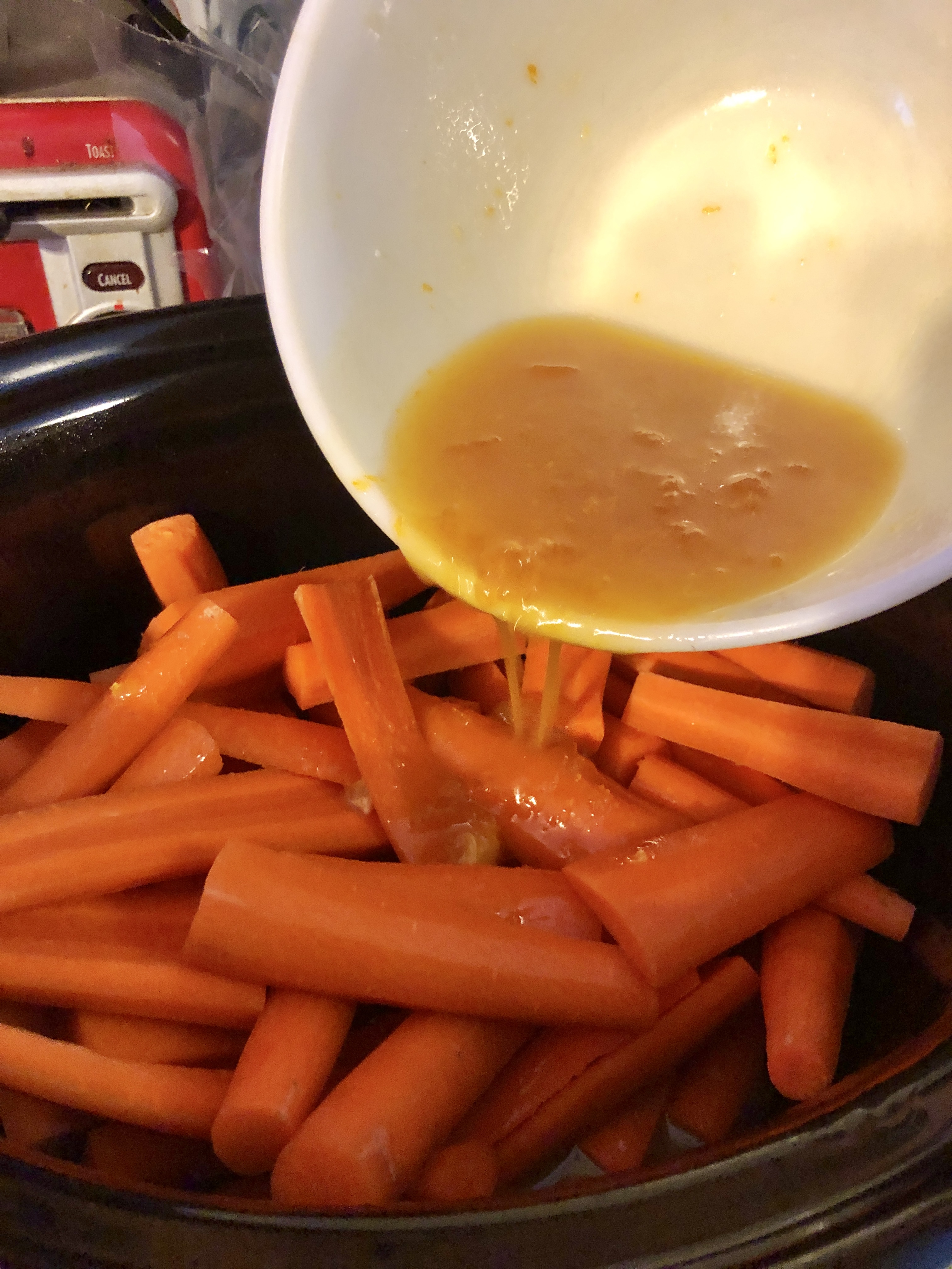 Adding Orange Apricot Glaze over the top of carrots in a slow cooker.